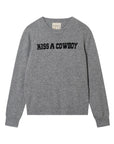 The Kiss A Cowboy Crew by Jumper 1 2 3 4/CR2 is a grey crew neck jumper with bold black “KISS A COWBOY” lettering on the chest, finished with ribbed cuffs and hem for a classic, cozy look.