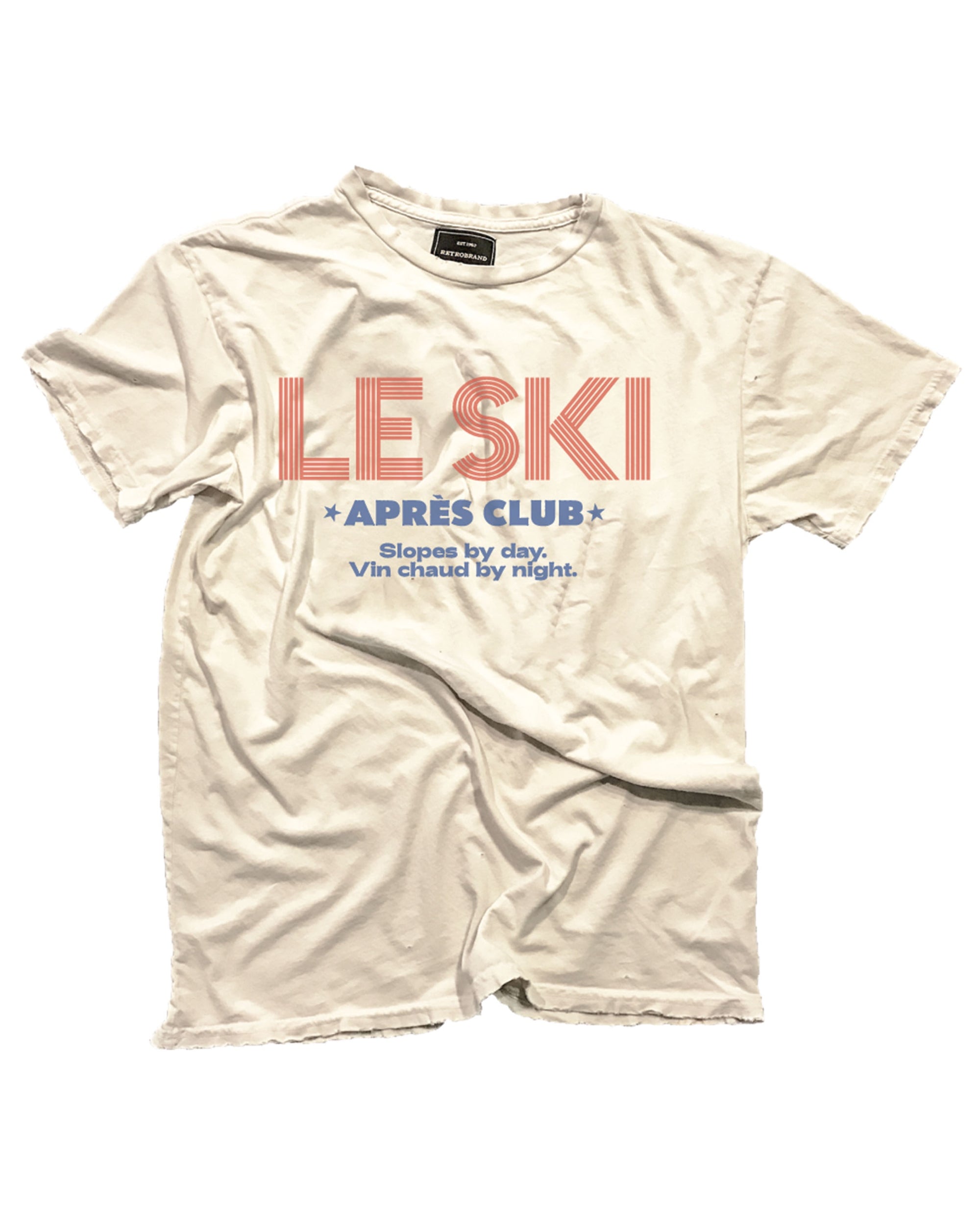 The Le Ski Apres Club tee by Wildcat Retro Brands is a cream-colored, vintage-washed shirt with bold red "LE SKI" and blue "APRÈS CLUB," plus "Slopes by day, Vin chaud by night." in blue—a classic après-ski look.