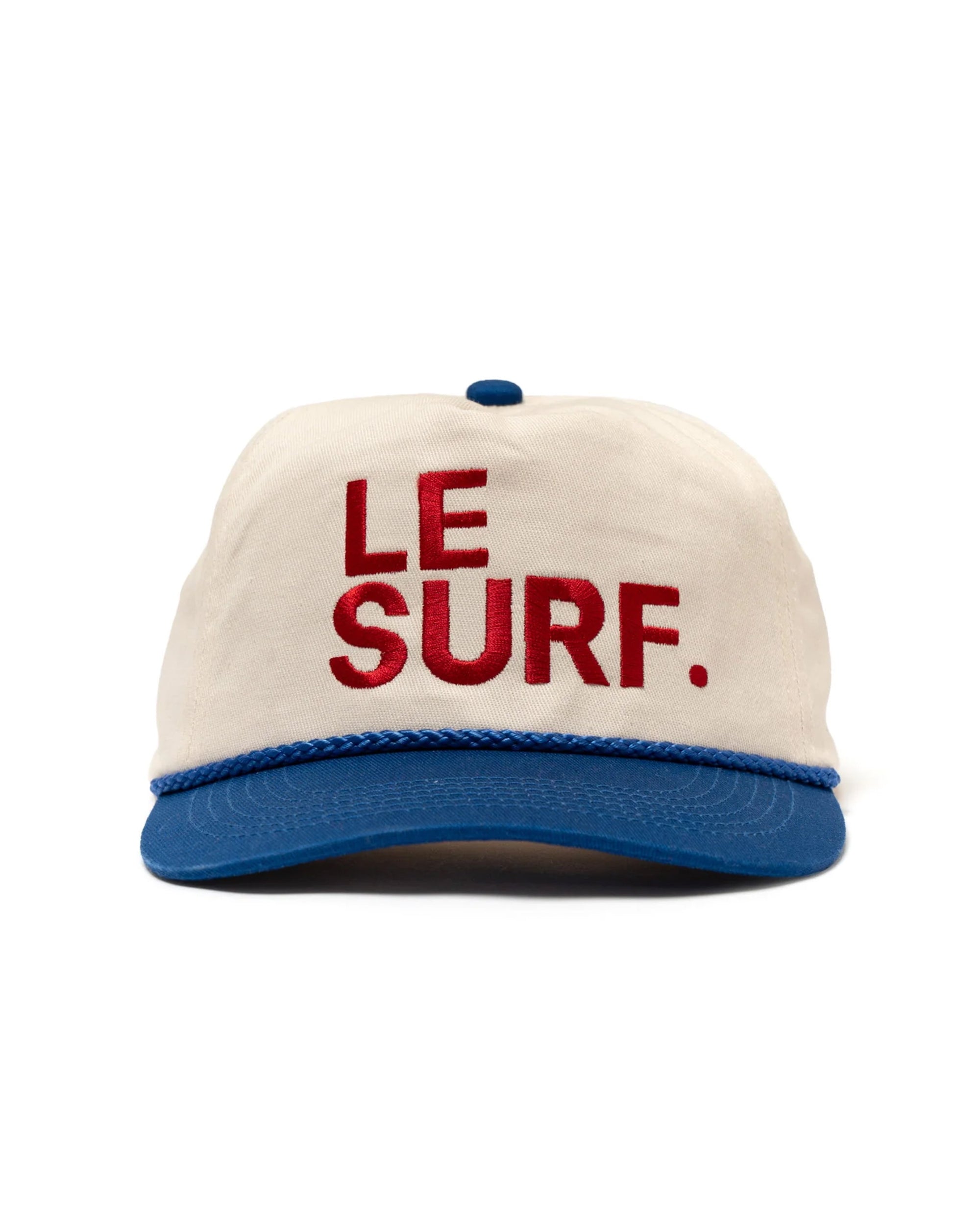 The Le Surf Vintage Lesure Icon Cap by Ping Pong Surf Club is a white cotton snapback with a blue flat brim and button, featuring "LE SURF." embroidered in bold red letters on the front.