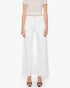 A person wears The Lemon Twist Skimp by Mother—high-rise, wide-leg cotton-blend pants—paired with a beige cropped top and black open-toe heels, standing against a white background.