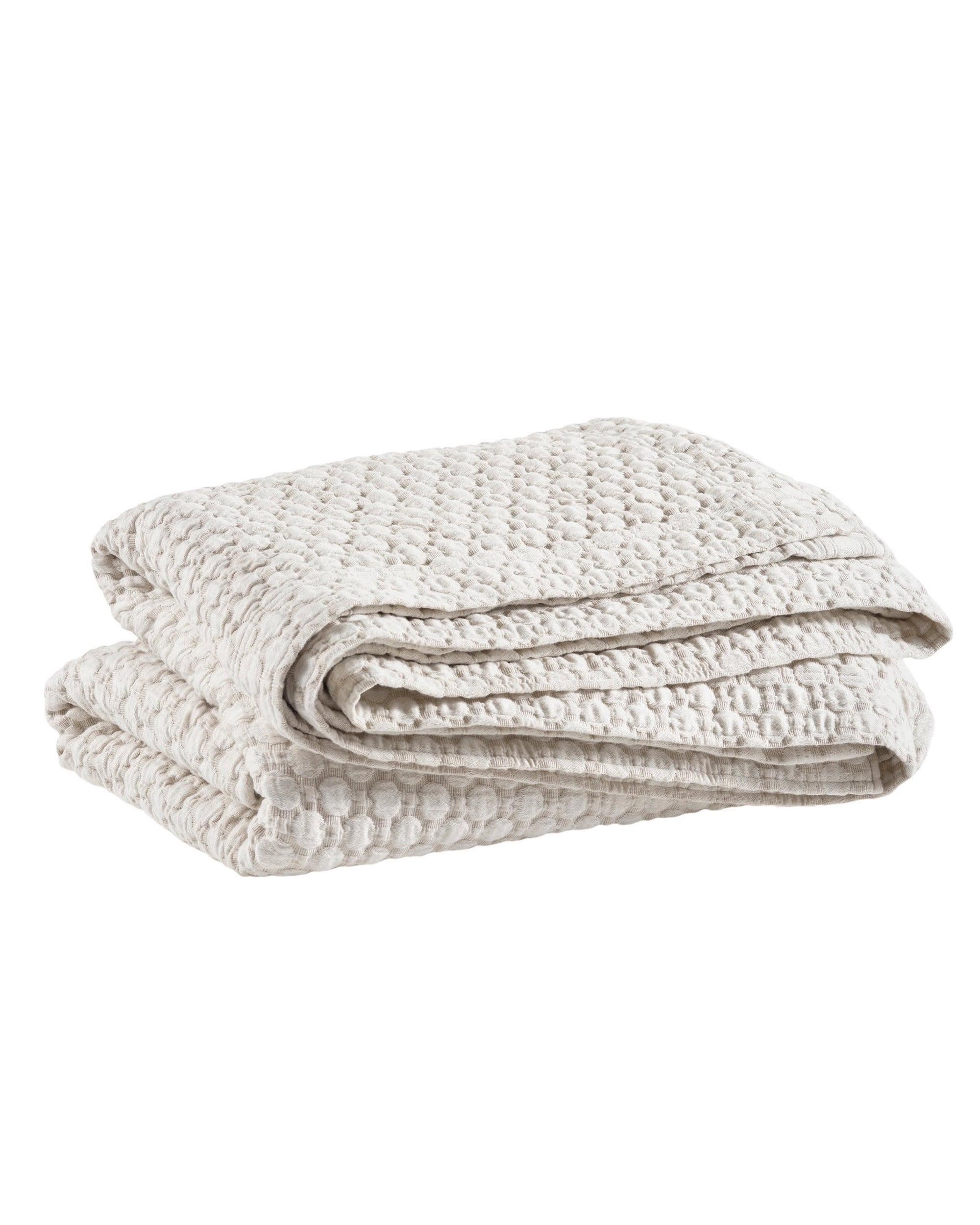 The Pinecone Hill Lodi Matelasse Coverlet is a light beige, waffle-knit blanket with a textured pattern, shown folded against a white background.