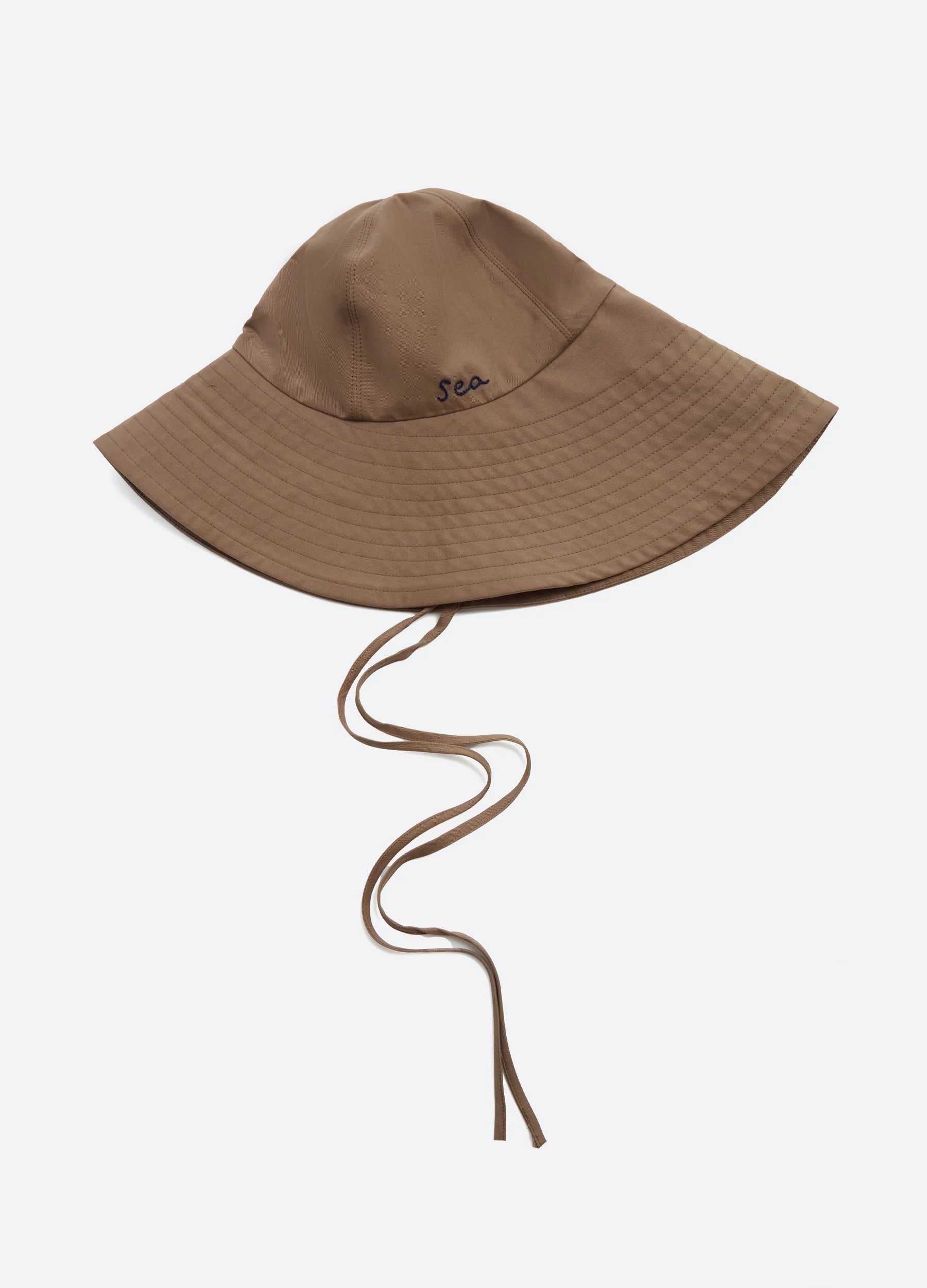 The Lois Twill Hat by Sea New York is an oversized brown sun hat with chin straps and "sea" embroidered in small, dark blue letters on the front, shown against a plain white background.