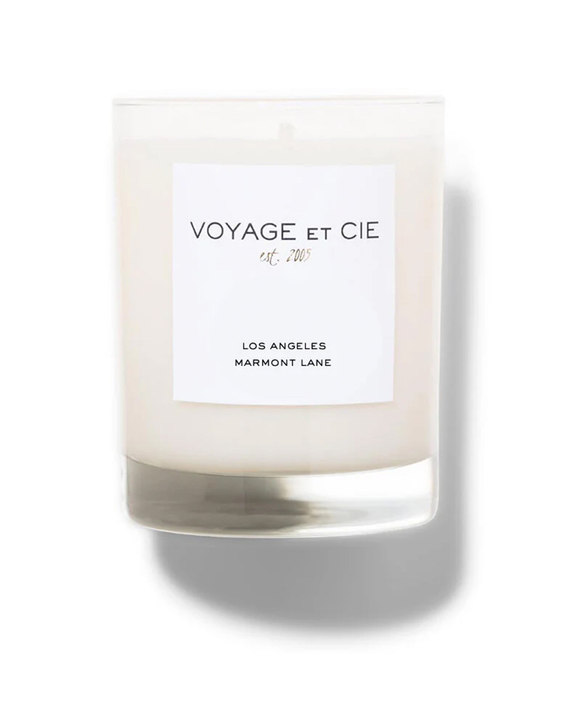 A 14 oz Classic Highball candle by Voyage Et Cie in a clear glass jar with a white label reading "VOYAGE ET CIE est. 2005" and "LOS ANGELES MARMONT LANE." White soy coconut blend. Perfect for scented candle lovers.