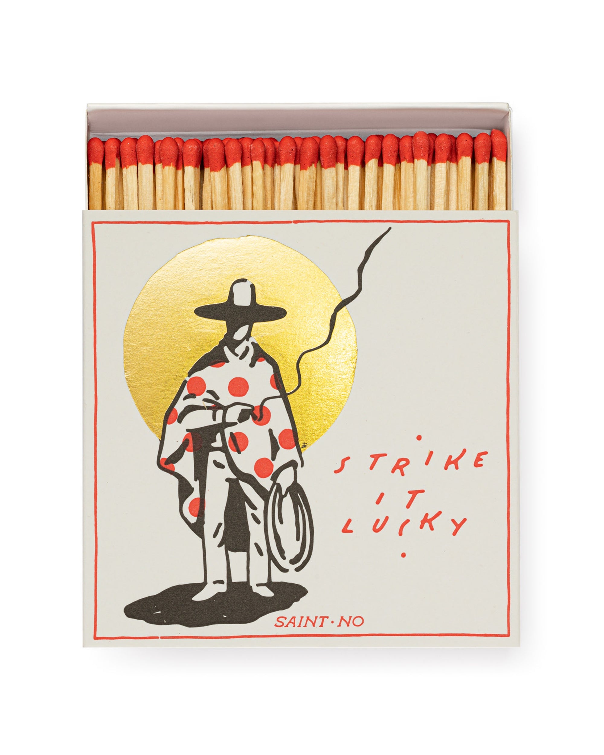 Faire Matches/Square features an open matchbox design with red-tipped matches. Its cover shows a stylized figure in a hat and polka-dot cape with a gold circle, plus the text “STRIKE IT LUCKY” and “SAINT NO.” for unique flair.
