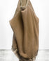 A tan, oversized Lucky Rabbits Sweatshirt by Free City (sparrow, LLC) hangs on a hook against a white wall and concrete floor, featuring lightweight French terry fabric that drapes softly with partially visible sleeves.