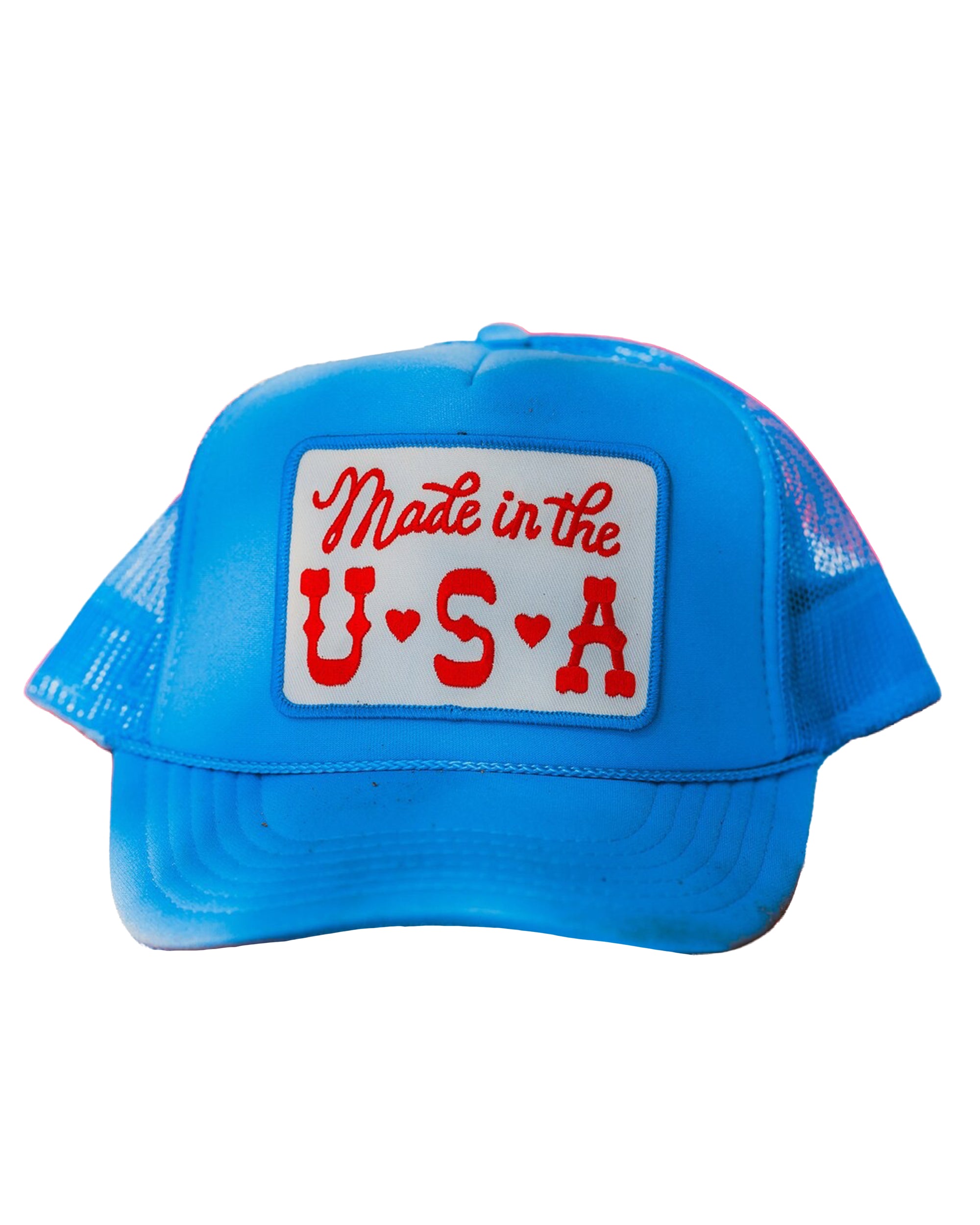 The Faire Made in the USA Patch Trucker Hat features blue mesh, an adjustable snapback, and a white front patch with bold retro red “Made in the U.S.A.” lettering. Photographed on a white background.