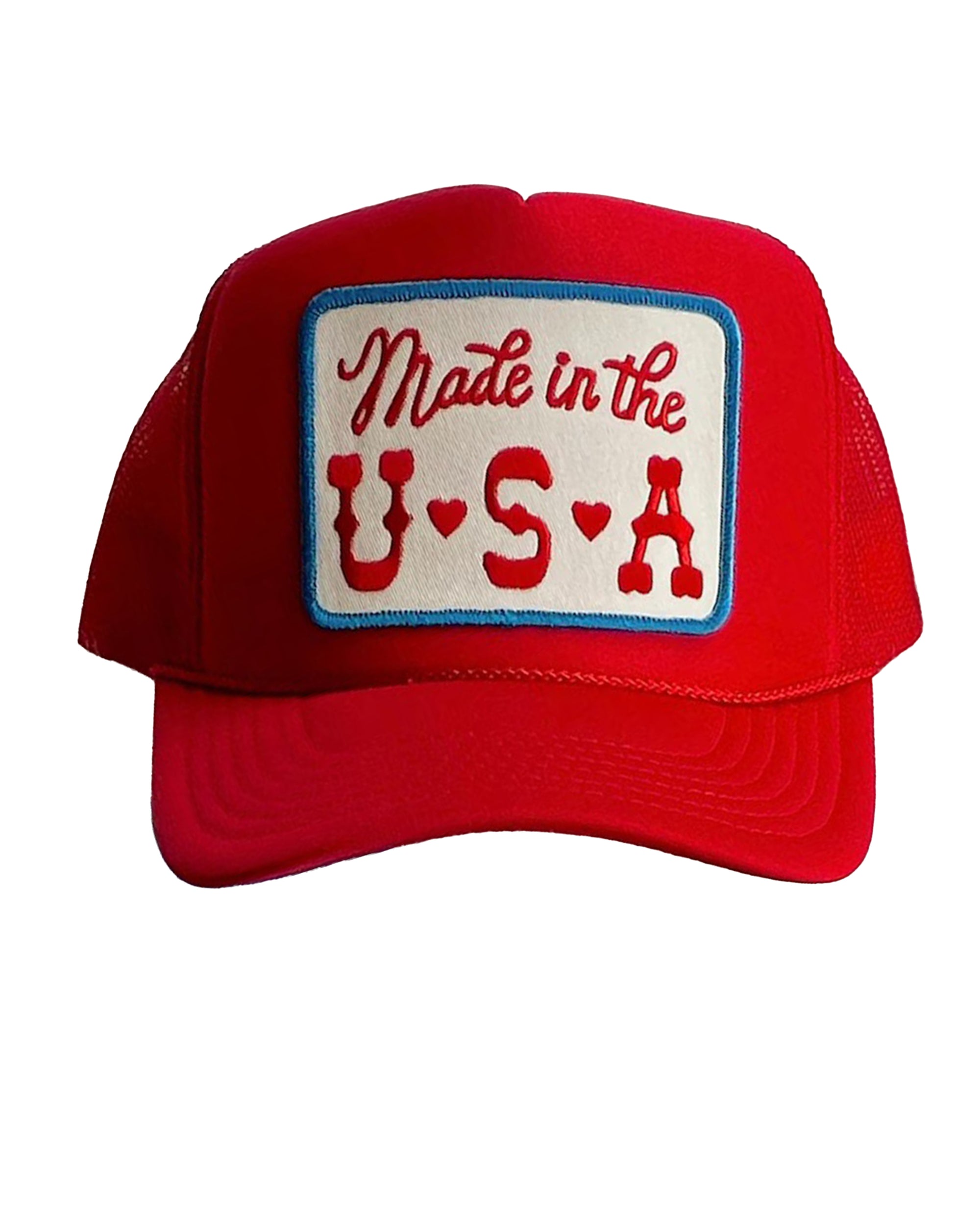 The Faire Made in the USA Patch Trucker Hat is a red cap with an adjustable snapback, blue trim, and a rectangular patch reading “Made in the U.S.A.” in red letters, accented by small red hearts between the letters.