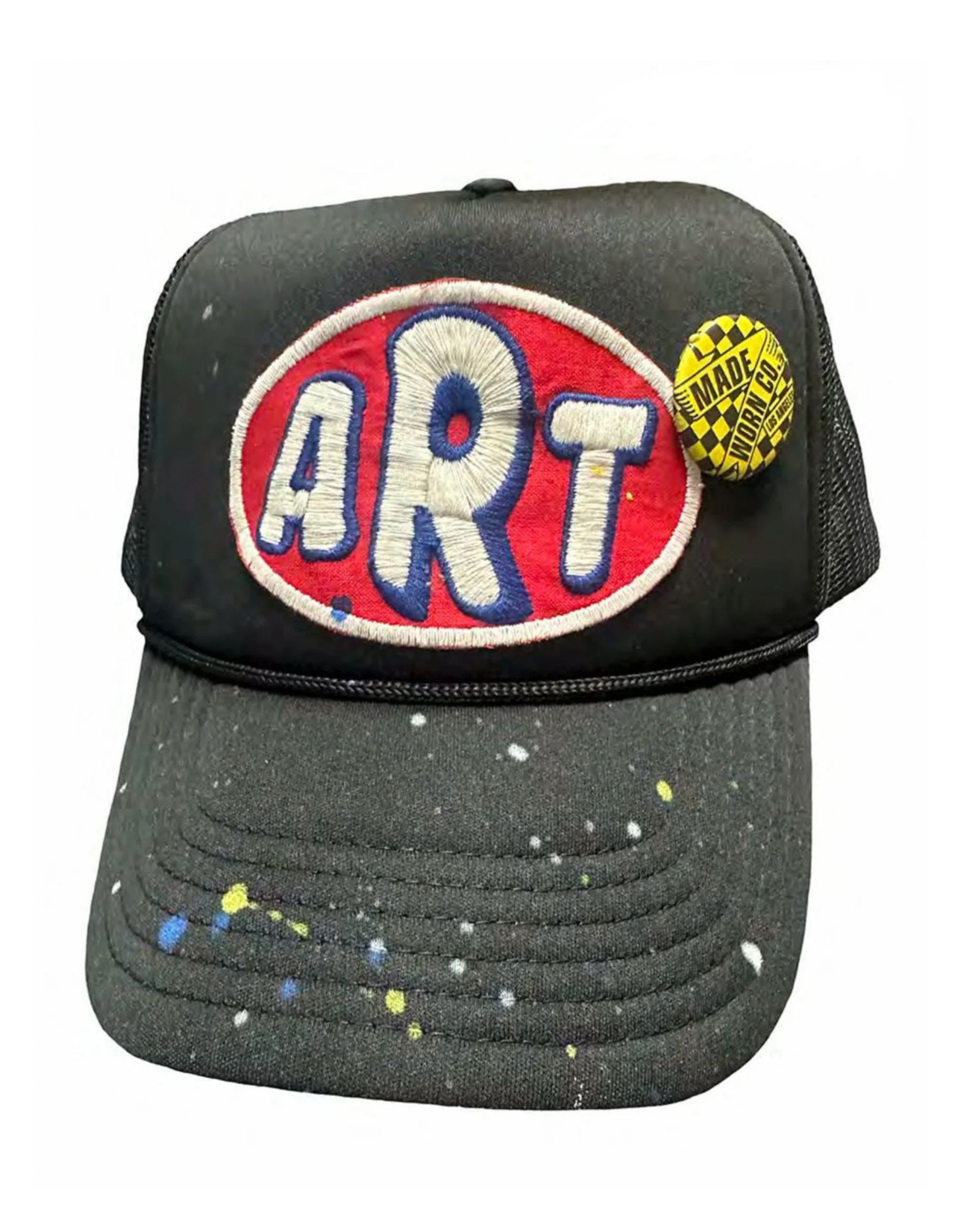 The MadeWorn Sponsor Hat by Made Worn is a black trucker hat with "ART" on a custom patch, yellow and white paint splatters, a yellow "MADE" pin, and an adjustable back strap for comfort.