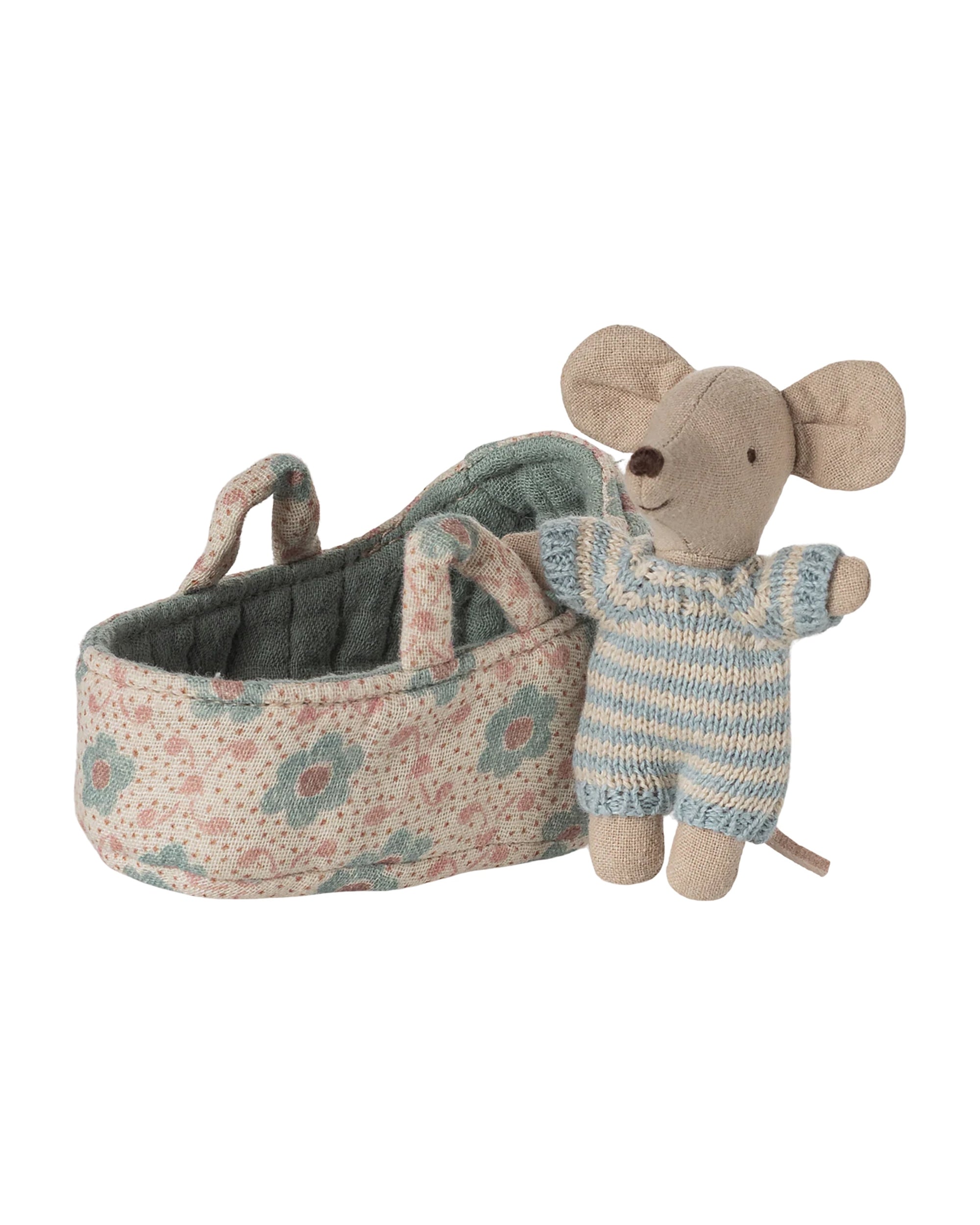 The Maileg Baby Mouse in Carry Cot by Maileg features a tiny mouse in a blue and white knitted suit, standing beside a floral-patterned fabric carry cot with two handles.