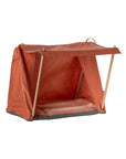 The Maileg Happy Camper Mouse Tent by Maileg is a small orange fabric tent with wooden poles and an open front, set on a striped cushion. Shown empty against a white background, it's ideal for imaginative play and outdoor adventures.