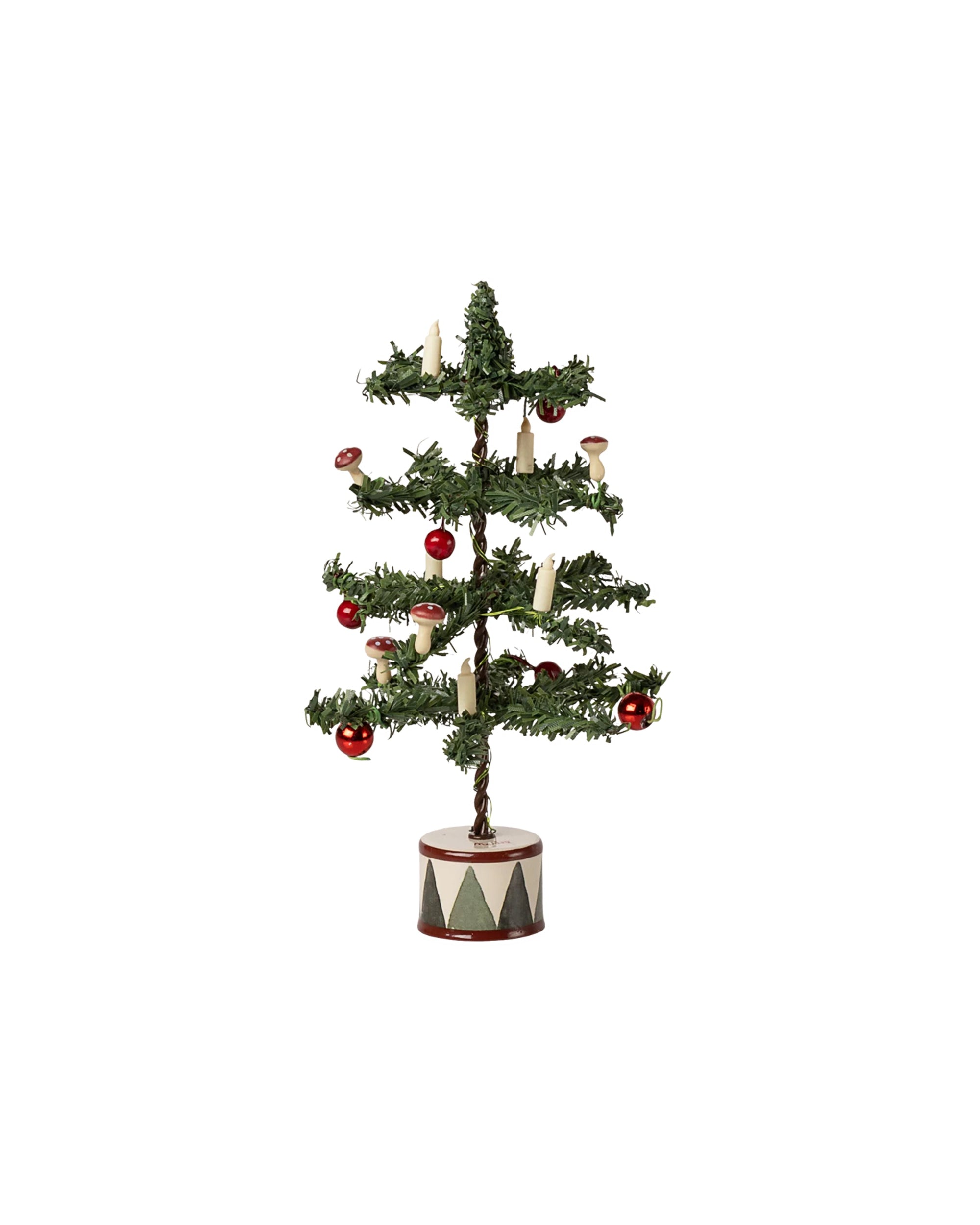 The Maileg Christmas Tree by Maileg features sparse green branches, red ornaments, white candles, and mushrooms in a round base with a red and white diamond pattern—perfect for festive charm next to a Gingerbread House.