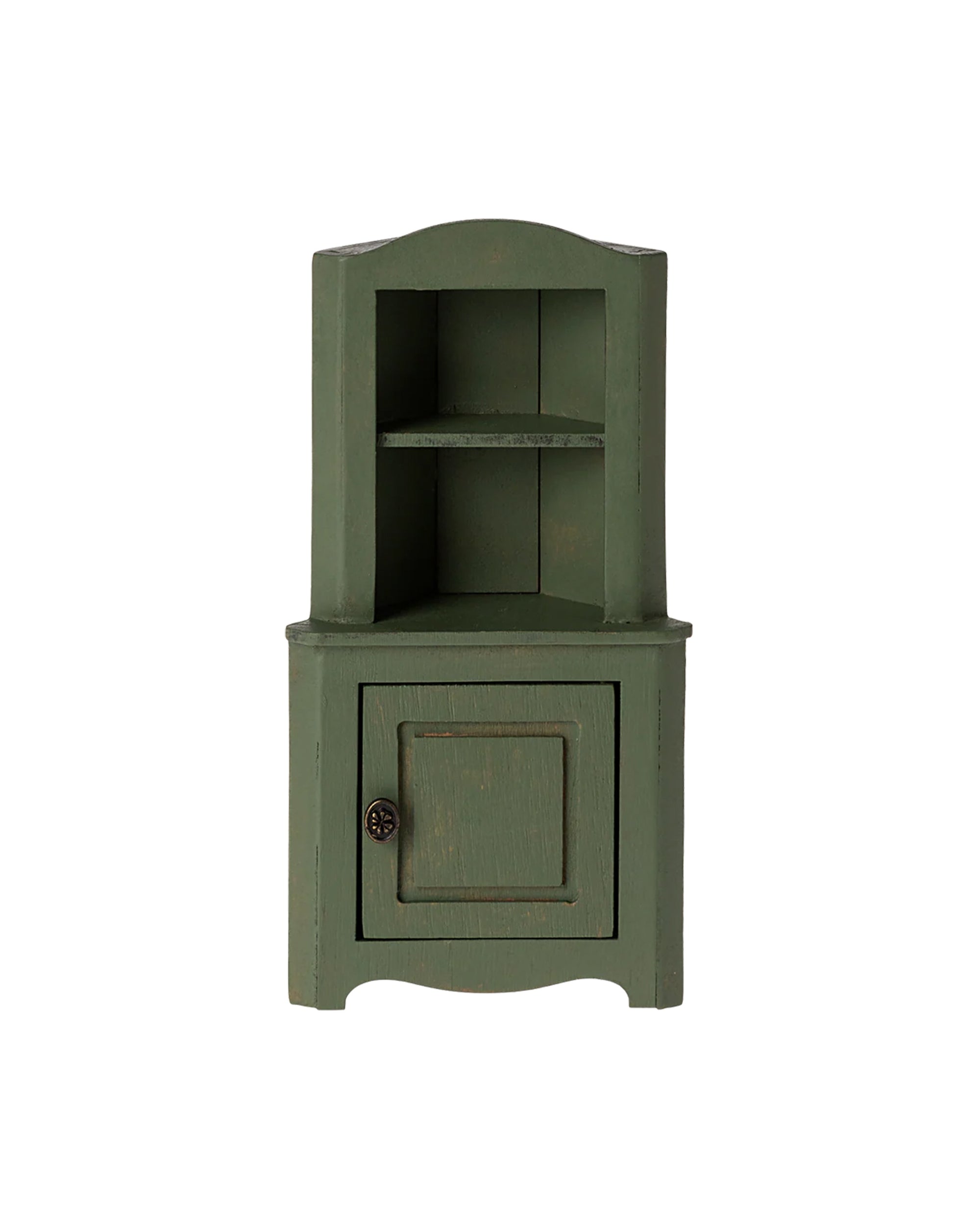 The Maileg Corner Cabinet by Maileg is a compact green wooden unit with an upper shelf and a closed door below, providing space-saving storage. It is shown against a plain white background.