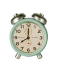 The Maileg Alarm Clock is a small, vintage-style metal clock in mint green with silver bells and legs. It shows 12:00 on a face with black numbers and "REPEAT" and "ALARM" printed.