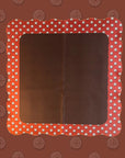 The Wild West Mahjong Mat ONLY by Faire features a rectangular, blank surface with red, scalloped, wavy borders adorned with white polka dots and a reddish-brown background patterned with repeating compass-like designs.