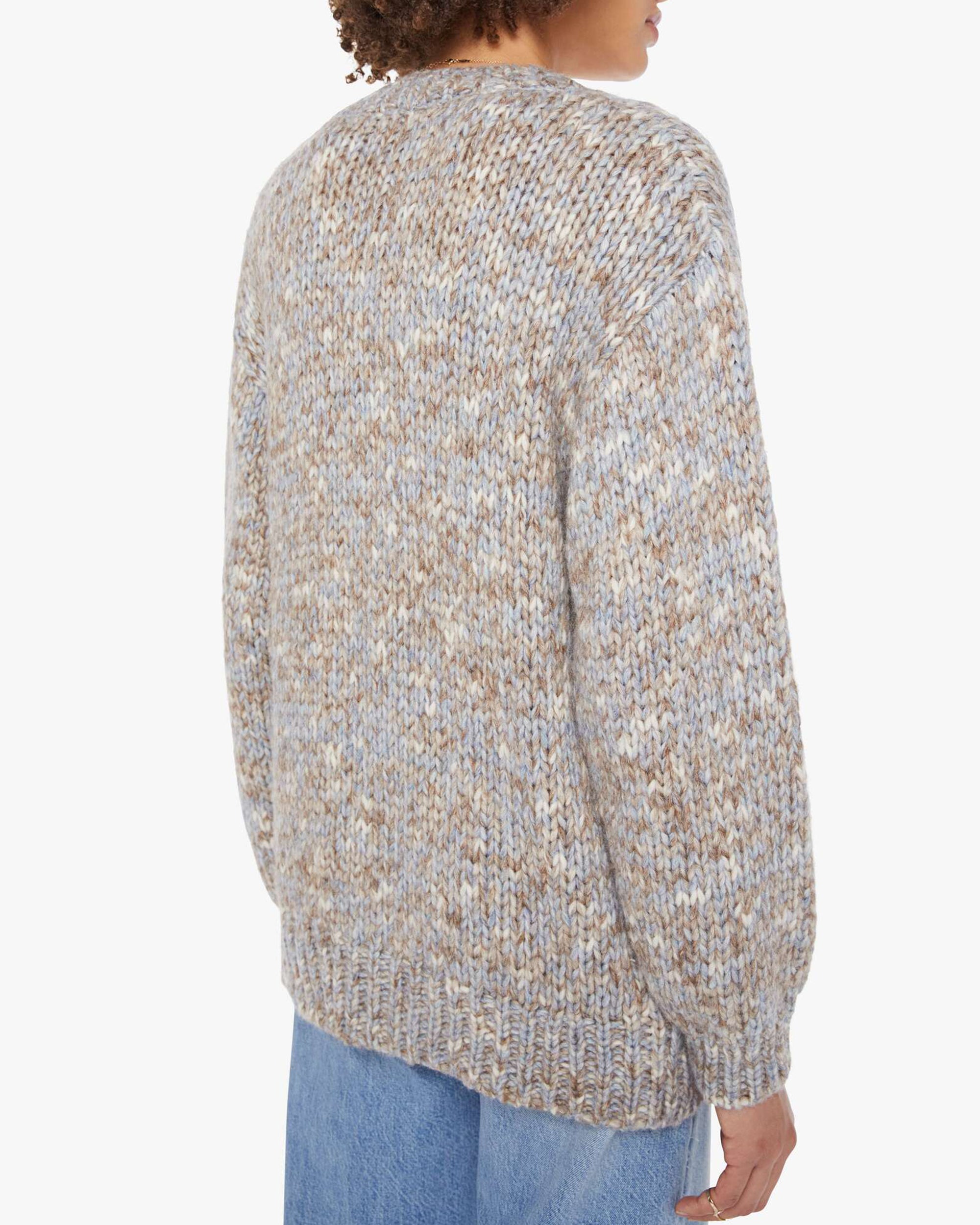 A person is seen from behind wearing the Marvin Sweater by Xirena, a chunky knit oversized cardigan in multicolored beige and gray with long sleeves, paired with light blue jeans against a plain white background.