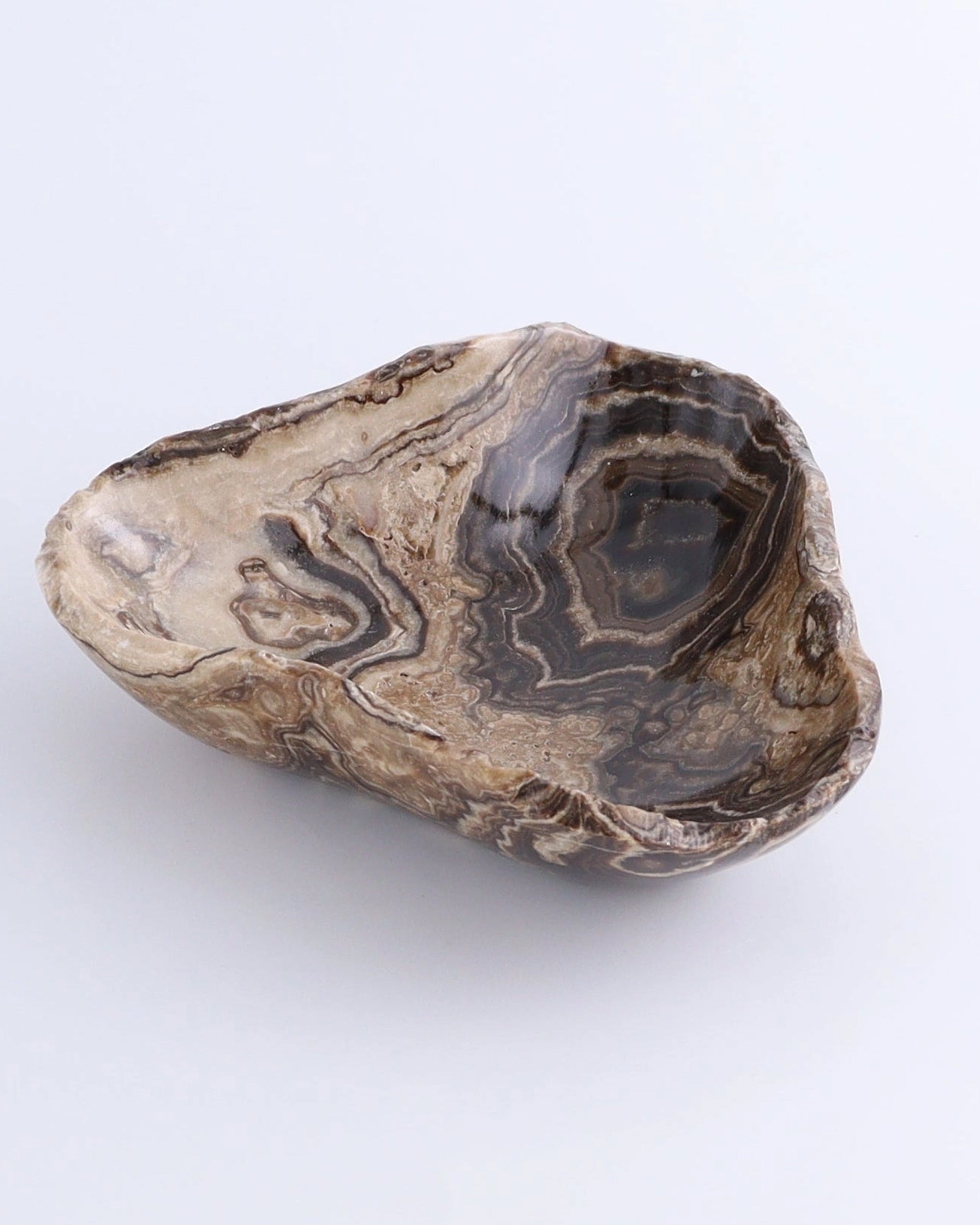 Small triangular bowl in polished brown and beige onyx by Faire, with swirling stone patterns, shallow profile.