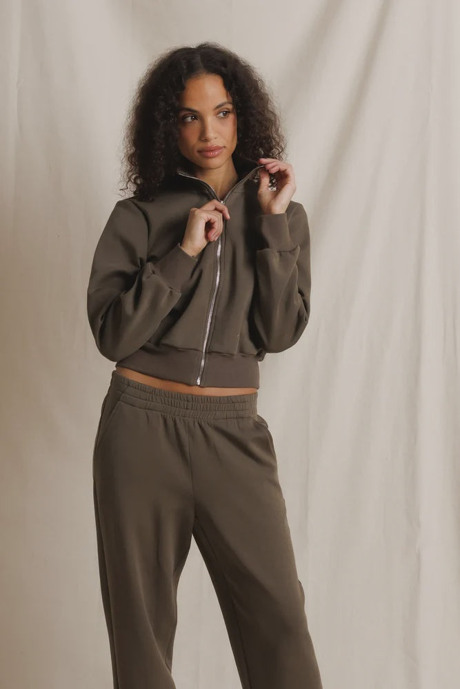 Olive Milana Track Jacket by Perfectwhitetee, modeled in front of a light beige fabric backdrop.