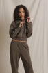 Olive Milana Track Jacket by Perfectwhitetee, modeled in front of a light beige fabric backdrop.