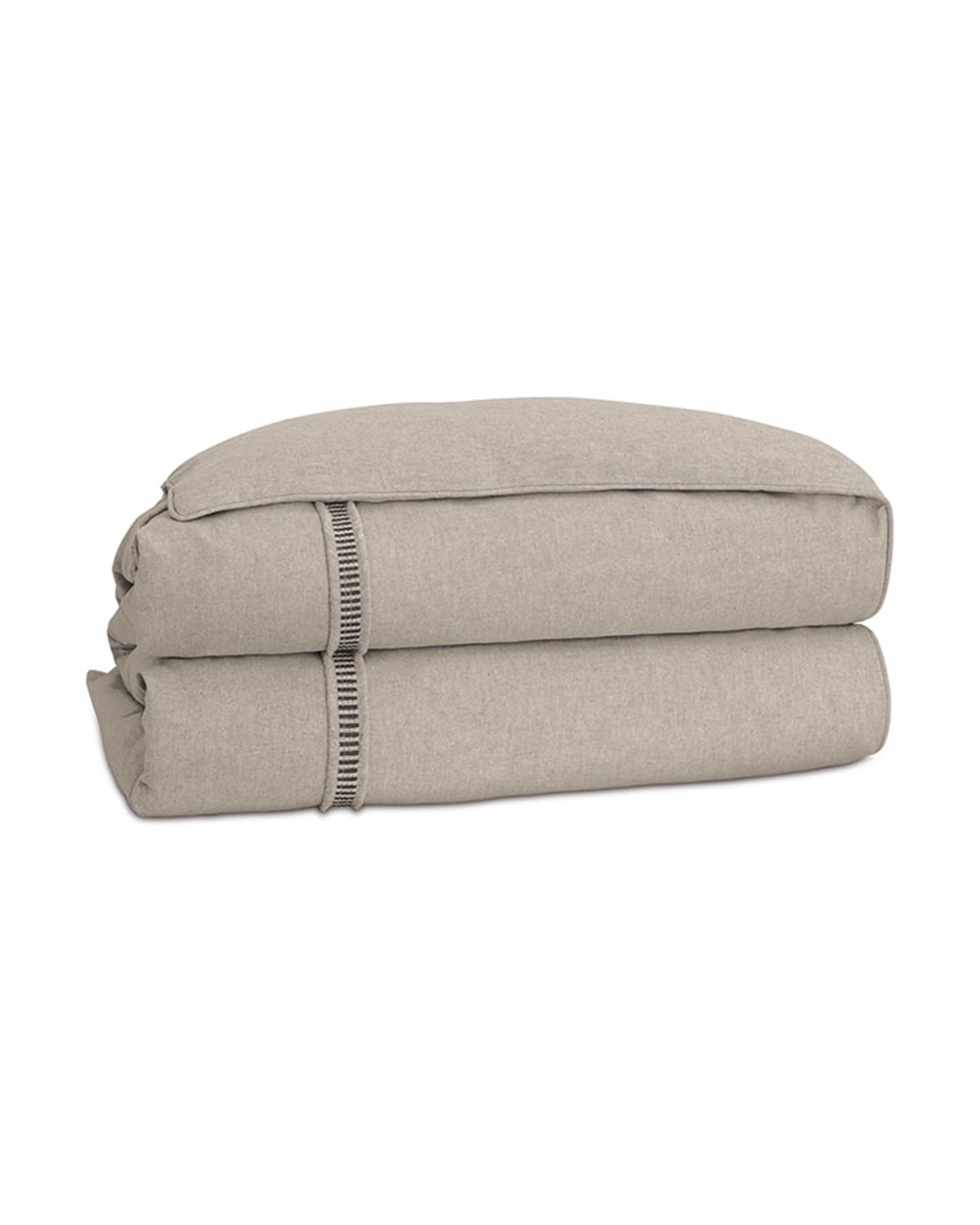 The Moab Textured Comforter by Eastern Accents features decorative edge stitching and soft poly batting in a neatly folded beige linen design, displayed on a white background.