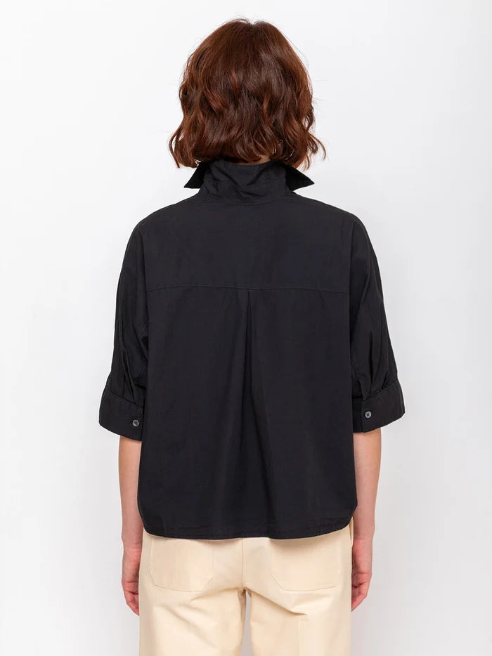 Black Monday12 Daria Shirt and beige pants from back, styled on model with short brown hair.