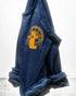The Artyard SUPERSHOP STAMP Raglan by Free City (sparrow, LLC) is a navy blue unisex sweatshirt with rolled cuffs, made in the USA. It features a large yellow-orange graphic and "thecitycalmbooks yard shop" on the chest.