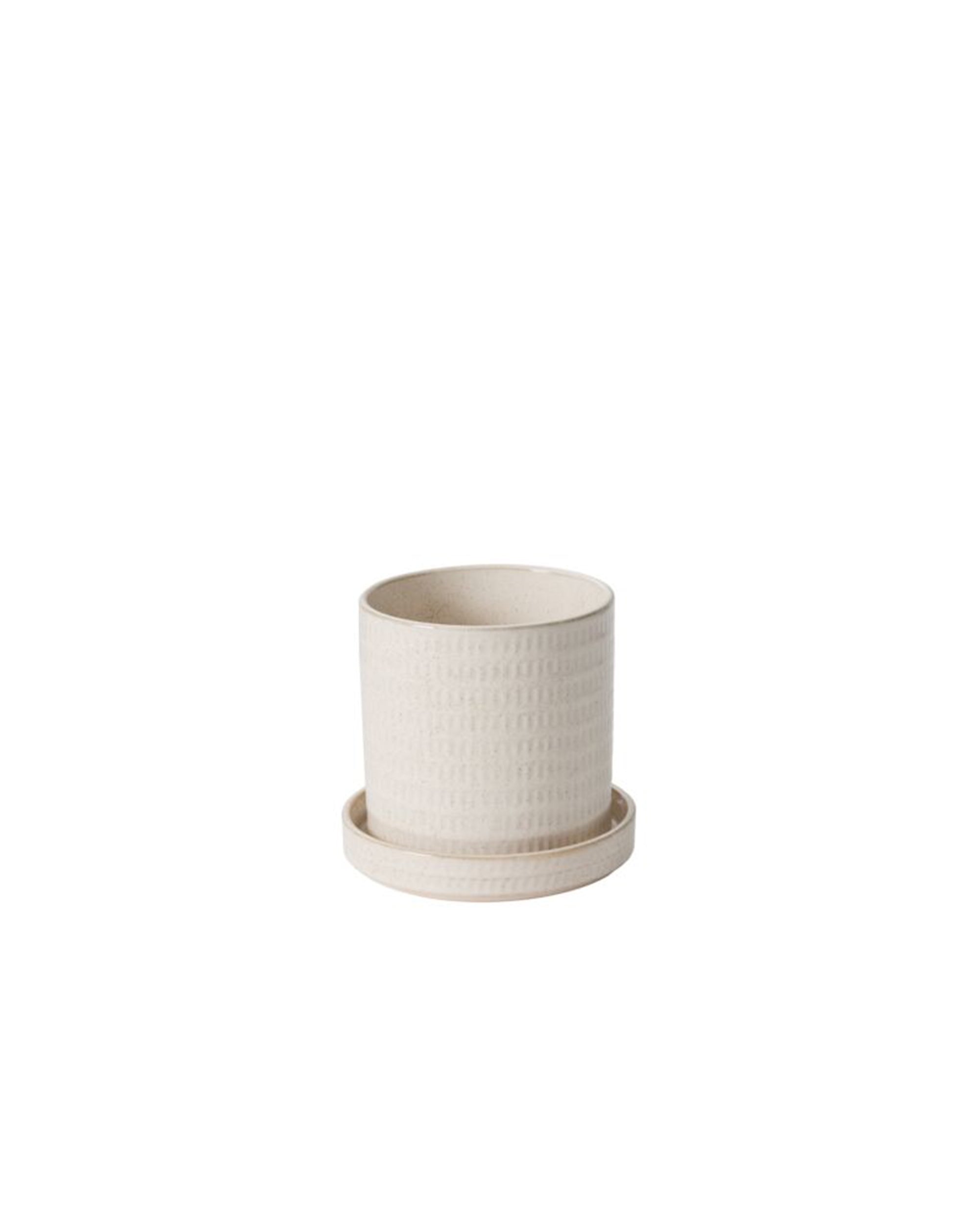 The Accent Decor 50735 Morse Pot w/Saucer is a small, light beige ceramic planter featuring a subtle textured design, drainage hole, and matching shallow saucer, shown on a plain white background.