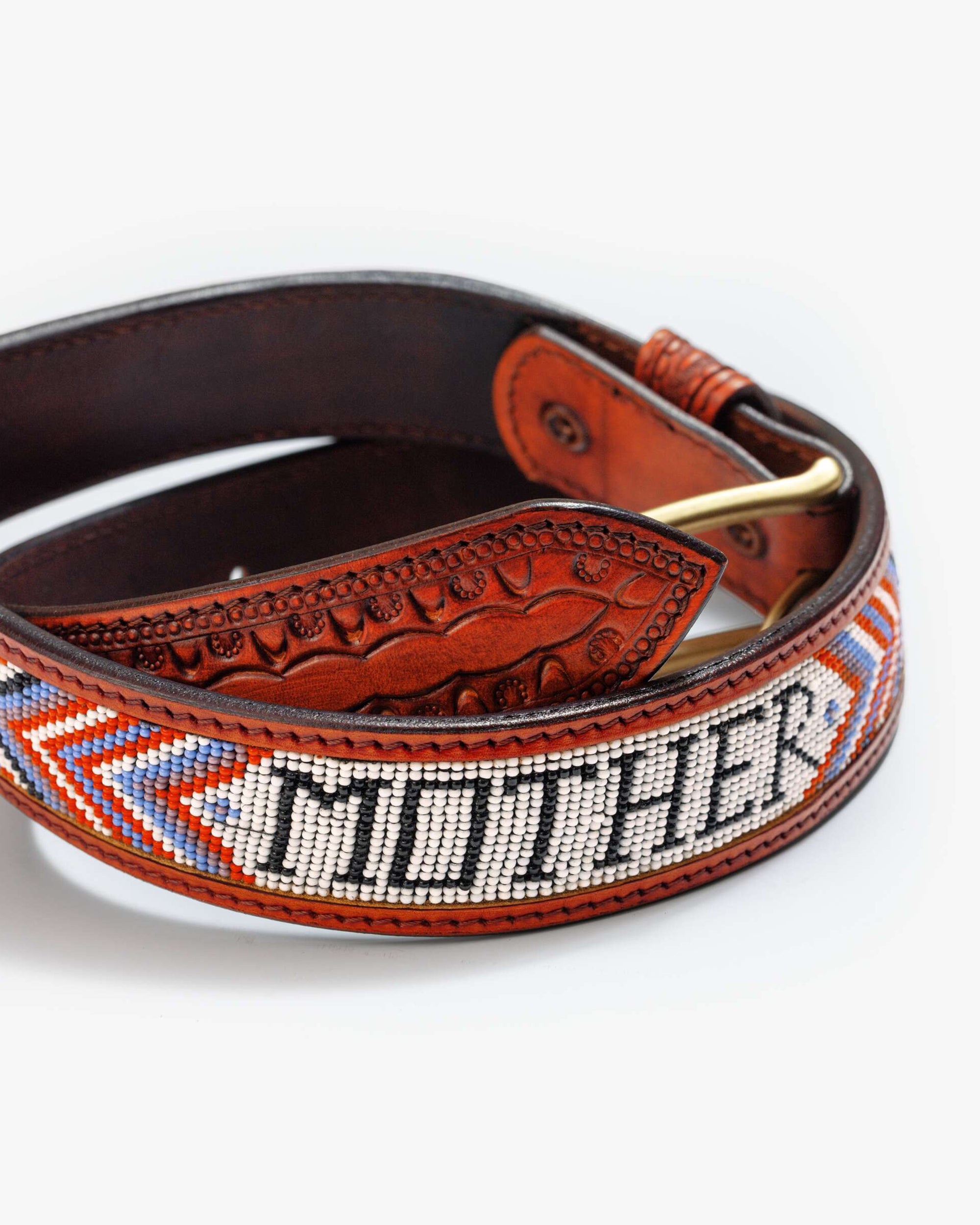 The Eye Opener by Mother is a vintage brown cow leather belt featuring "MOTHER" spelled in white, black, and gray beads, with vibrant blue, orange, and red geometric patterns along the edges.