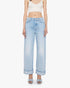 A woman stands against a plain white background wearing The Dodger Button Hover Cuff jeans by Mother, styled with a white cropped tank and light blue open-toe block heel shoes.