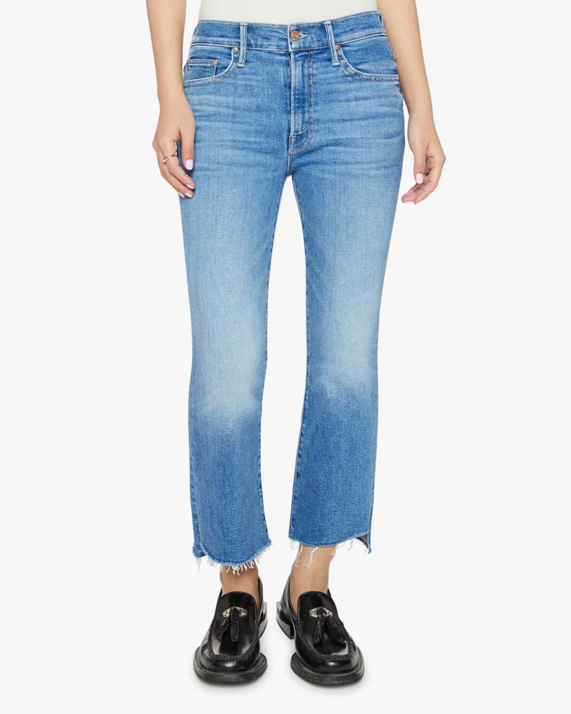 A person wears the Mother Lil Insider Crop Step Fray jeans in light blue stretch denim with high waist and frayed hems, paired with black loafers. The photo is cropped from waist to feet against a plain white background.