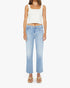 A woman wearing a white sleeveless crop top and gold sandals stands facing forward against a white background, styled in Mother’s The Mid Rise Rambler Zip Ankle Fray jeans.