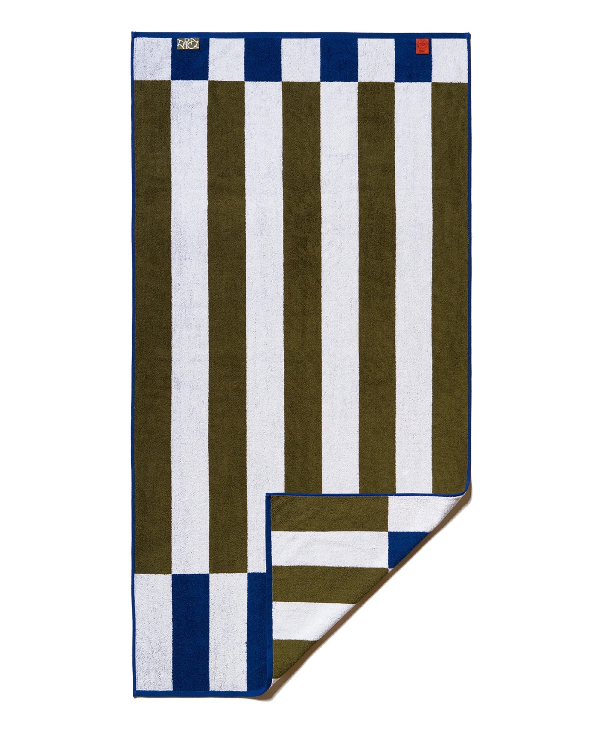 The Typical Navy/Moss Stripe Bath Towel is reversible with vertical moss green and white stripes, blue borders, a corner in reverse pattern, and two small tags on the top edge.