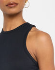 A person in a FRAME Racer Tank Dress and white pearl earring, with the image featuring the lower face, neck, and shoulder against a plain white background.