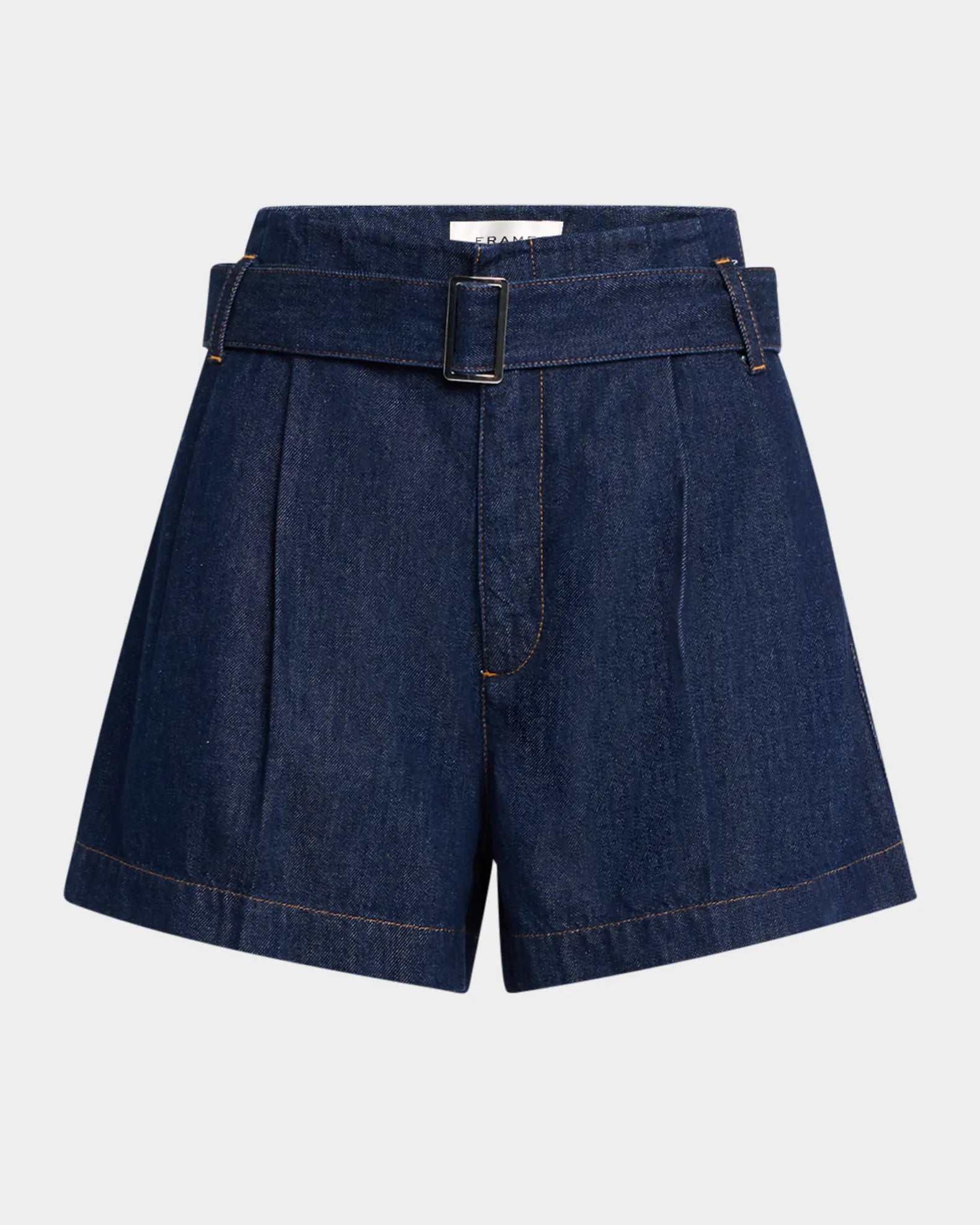 FRAME’s dark blue Paper Bag Short is crafted from lightweight denim and features a high waist with a wide belt and rectangular buckle. Pleated details add charm to their sleek design, set against a plain, light background.