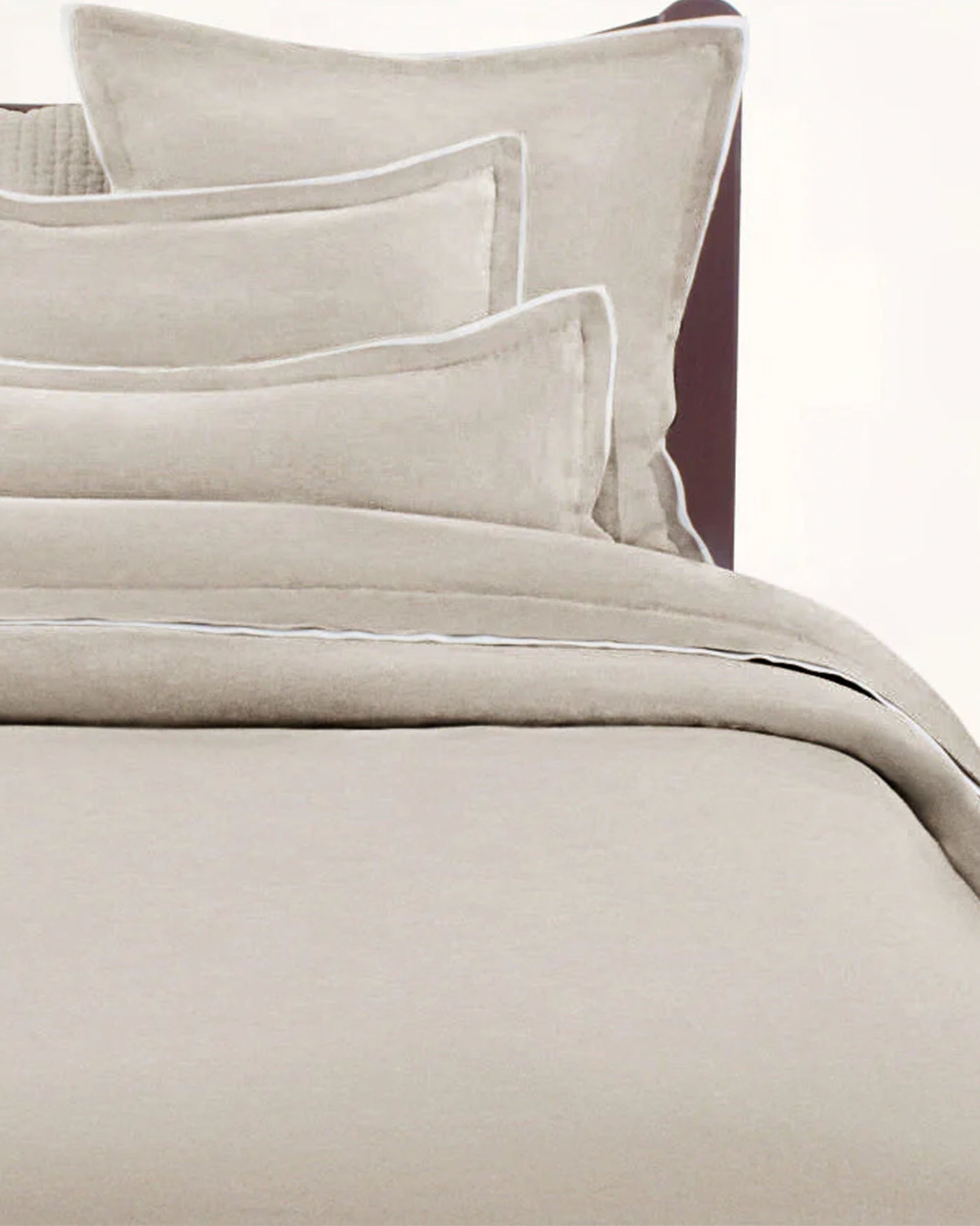 A neatly made bed features the Avasa Bedding Nolan Duvet in Natural King, paired with matching pillows, all in light beige Belgian flax linen, set against a plain background.