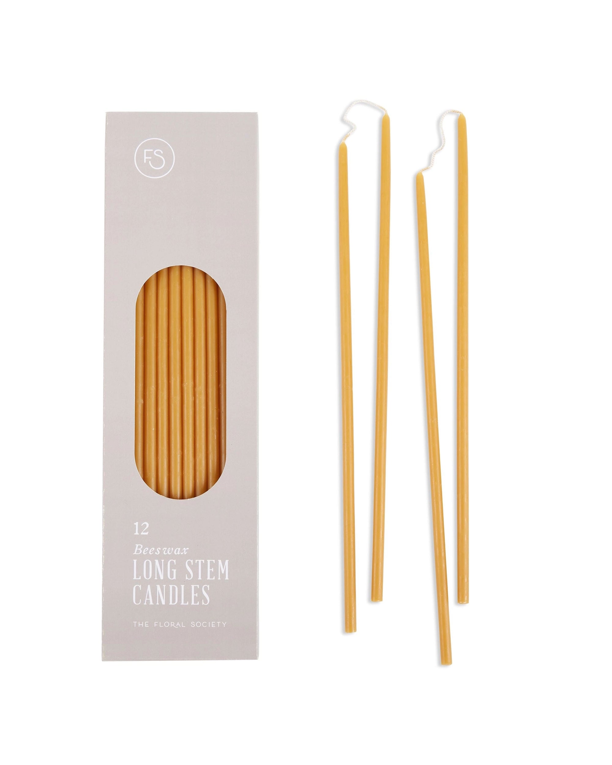 A box of "Long Stem Beeswax Candles" by The Floral Society contains 12 slender yellow tapers; three hand-dipped candles are shown outside, with one featuring a gently bent wick.