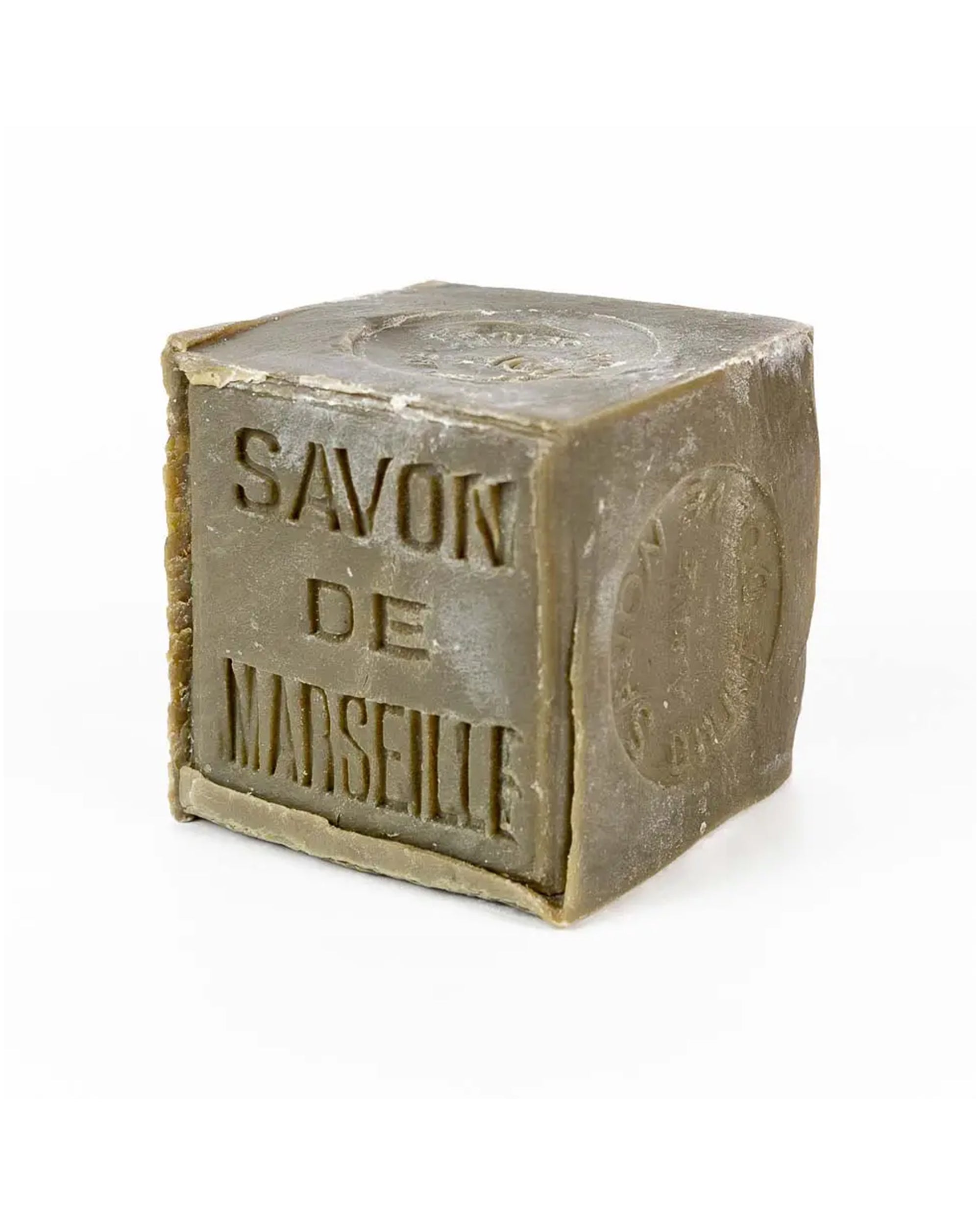 The Marseille Olive Oil Soap by Cie Luxe Brands is a cube-shaped French bar made with botanical oils, featuring embossed French text and a side stamp, all in a muted olive-green color.