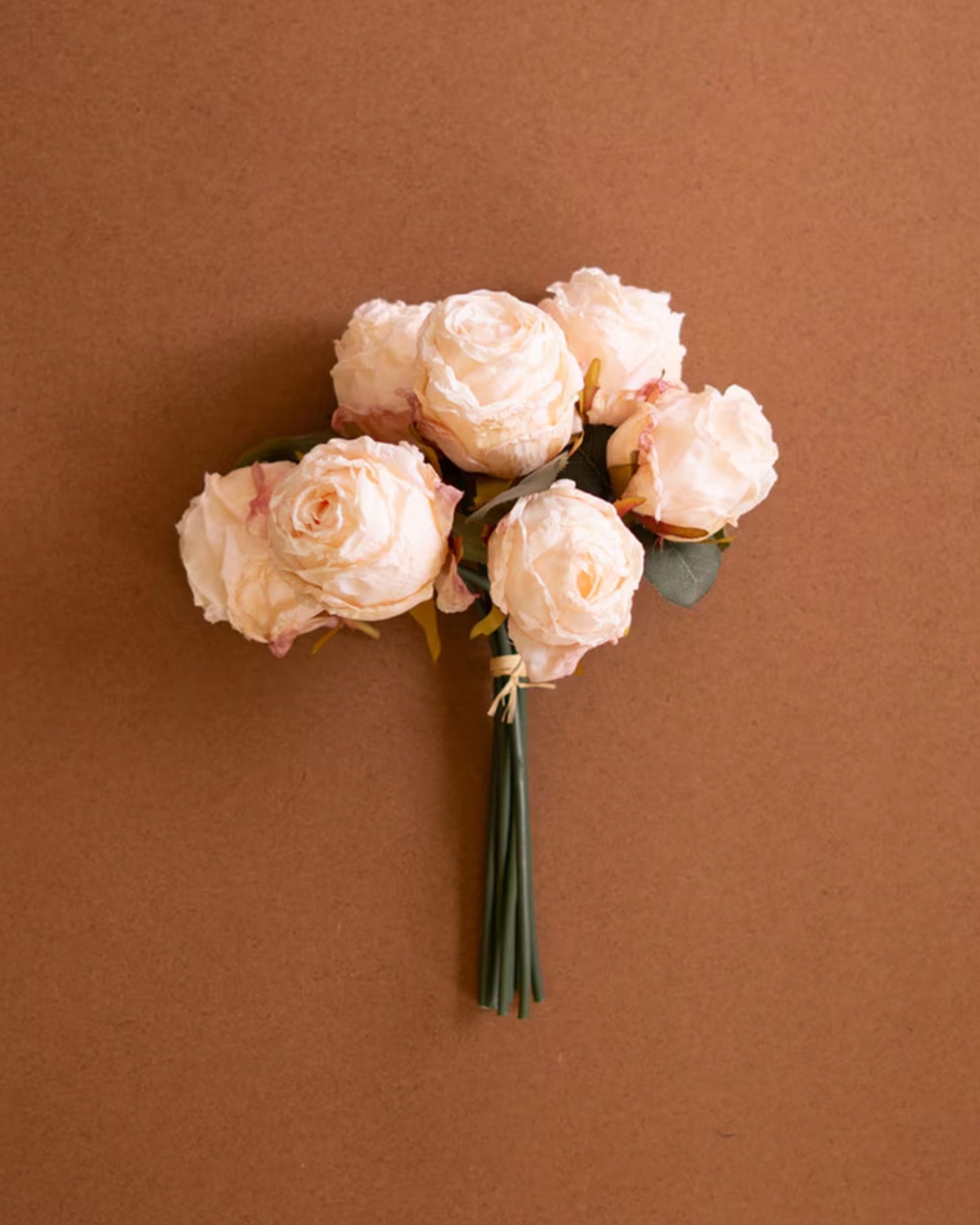 Petite pale pink roses with green stems, Kalalou Rose Bundle, displayed on a simple brown surface.