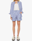 A person wears the Mother Drawn FreeBaller Short—blue and white striped, lightweight cotton—with a matching button-up shirt over a white top. The shirt sleeves are rolled up, one hand is in a pocket, tan sandals finish the look. Head not shown.