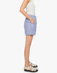 A person stands sideways against a plain white background in a white sleeveless top, beige sandals, and Mother’s The Drawn FreeBaller Short—blue and white striped cotton shorts with pockets.