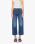 A person wearing a white short-sleeve top, Mother’s The Half-Pipe Ankle high-waisted jean in SUPERIOR denim, and dark blue sandals stands against a plain white background.