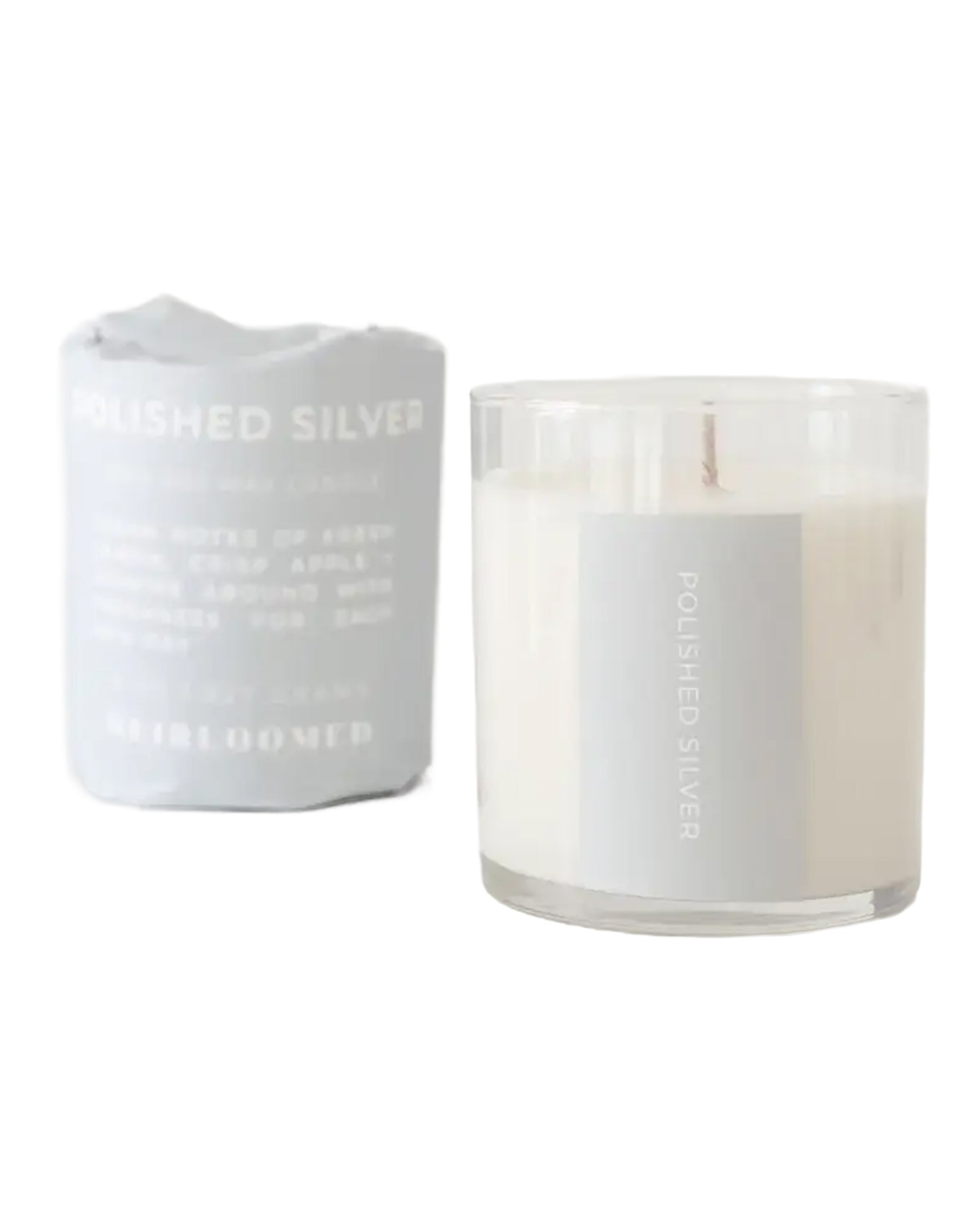 The Faire Polished Silver Candle, hand-poured soy wax in a clear glass jar, is shown next to its packaging against a white background. Enjoy its custom blended fragrance and clean burn for a refined atmosphere.