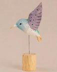 Purple hand-painted carved hummingbird on wire wings and wood base by Faire, decorative accent.
