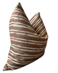 The Rennah Collective Radcliff Pillow 22x22 features a brown woven cover with white horizontal stripes, shown from an angled side view on a white background, bringing stylish flair to any space.