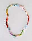 The Faire Gemstone Necklace, featuring handpicked beads and vibrant natural gemstones, shines in shades of red, pink, blue, green, yellow, and purple against a plain white background, adding a touch of elegance.