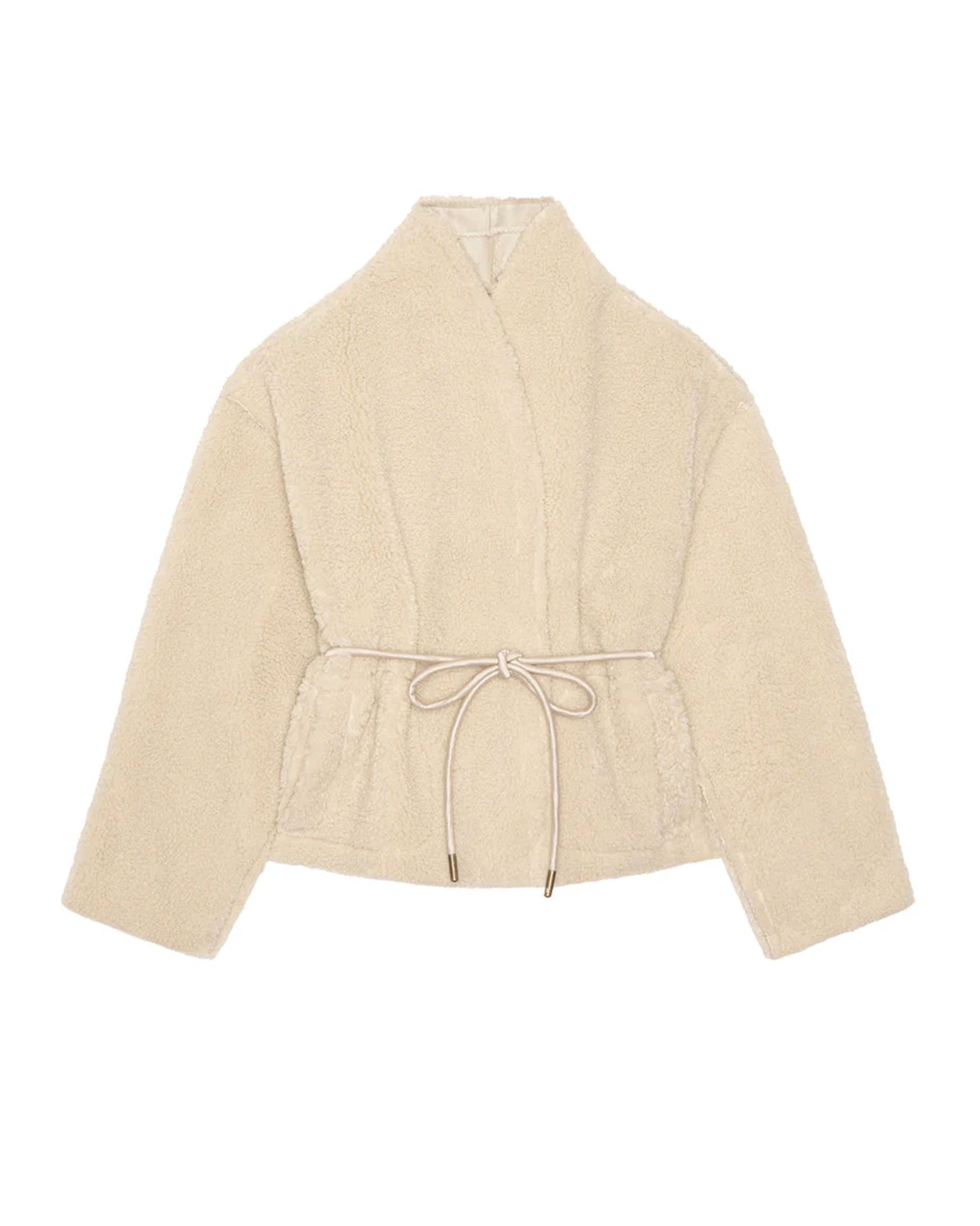 The Reversible Drover Coat by The Great Inc. is a cream-colored, fuzzy faux fur coat with long sleeves, wrap-style front, and belted tie waist, shown on a white background.