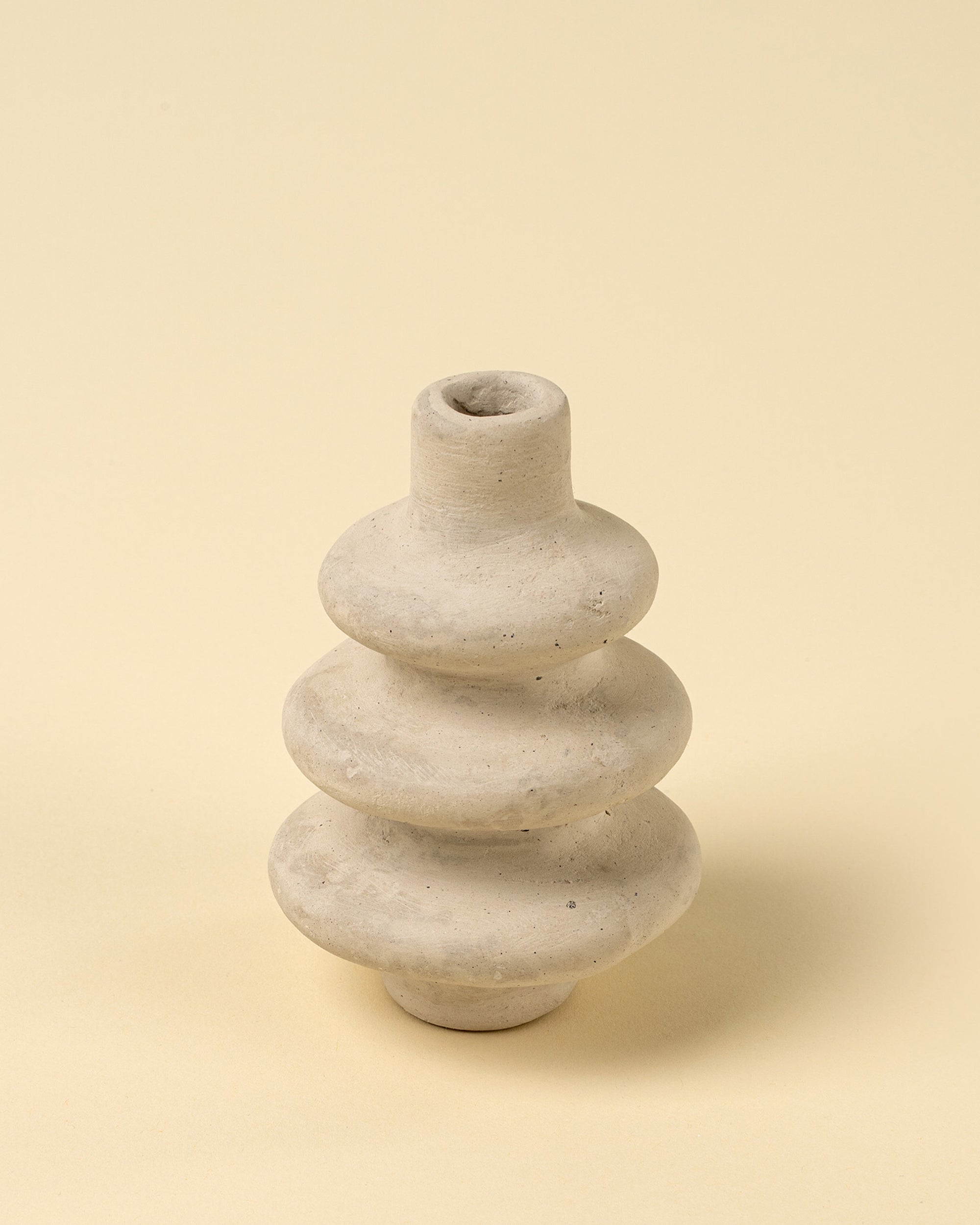 The Ripple Paper Mache Bud Vase by Indaba is a small, light gray handcrafted piece with three stacked ring-like sections and a narrow opening—perfect for sustainable decor in any space.