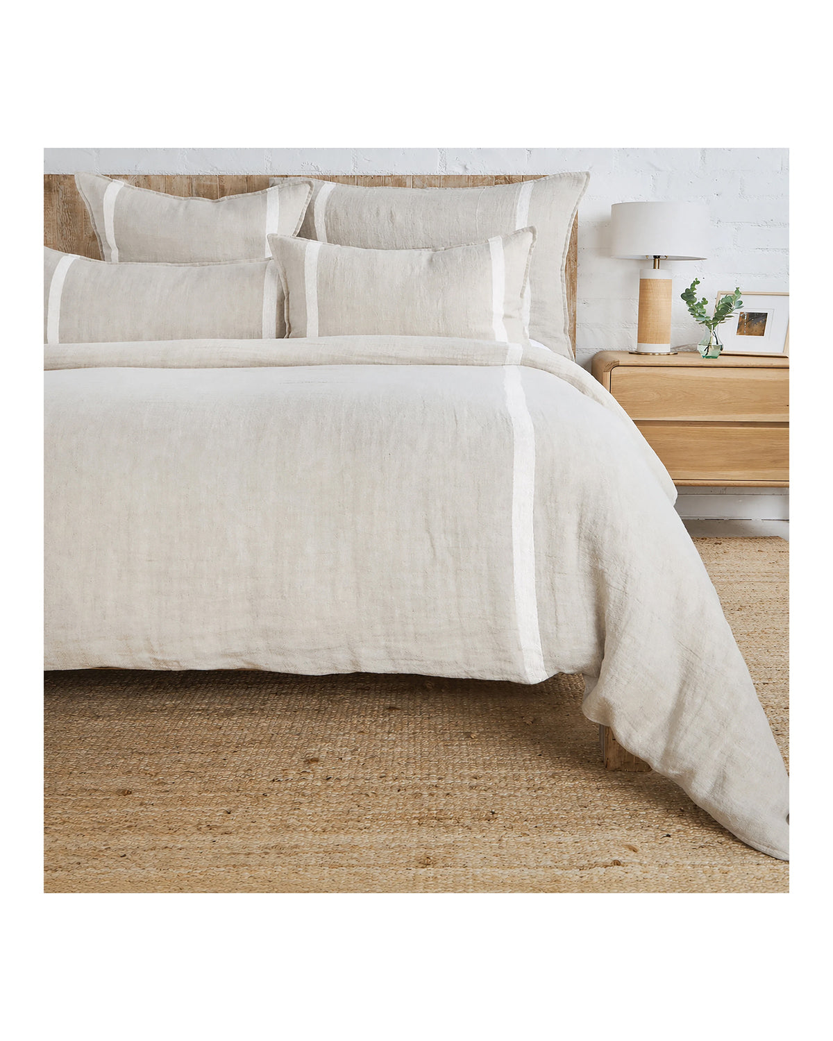 Beige linen queen duvet with white stripes and herringbone pattern by POM POM, styled beside a nightstand.