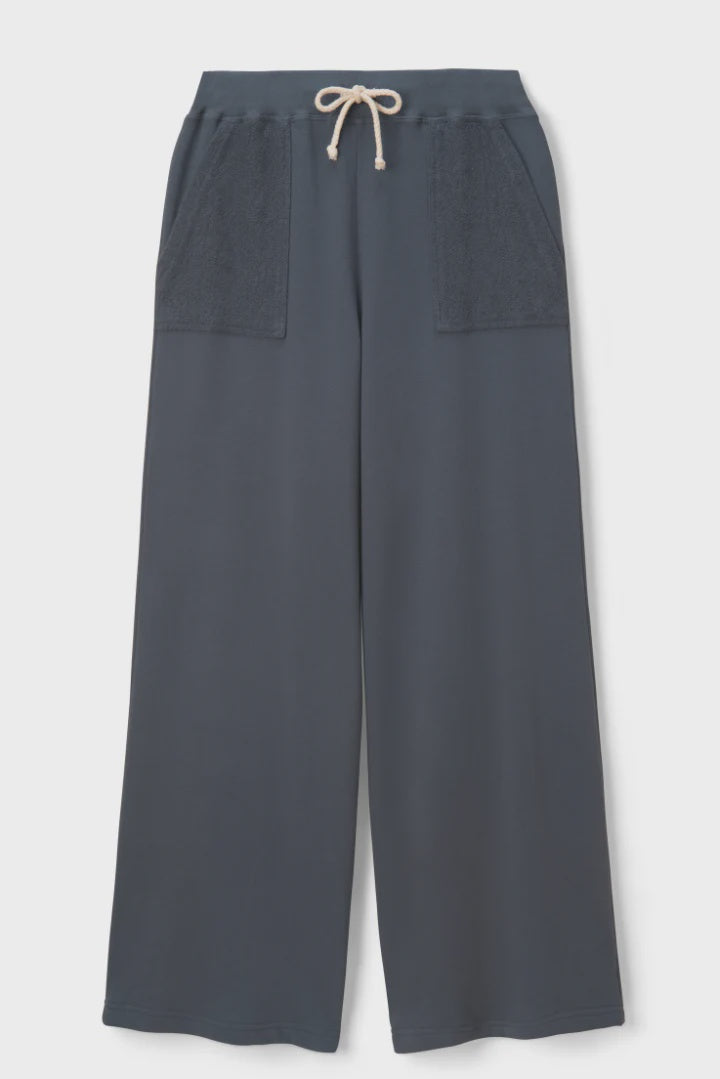 The Perfectwhitetee French Terry Pant is a wide-leg, navy cotton pant with an elastic waistband, beige drawstring, and two large textured front pockets. Pants are shown laid flat on a white background.