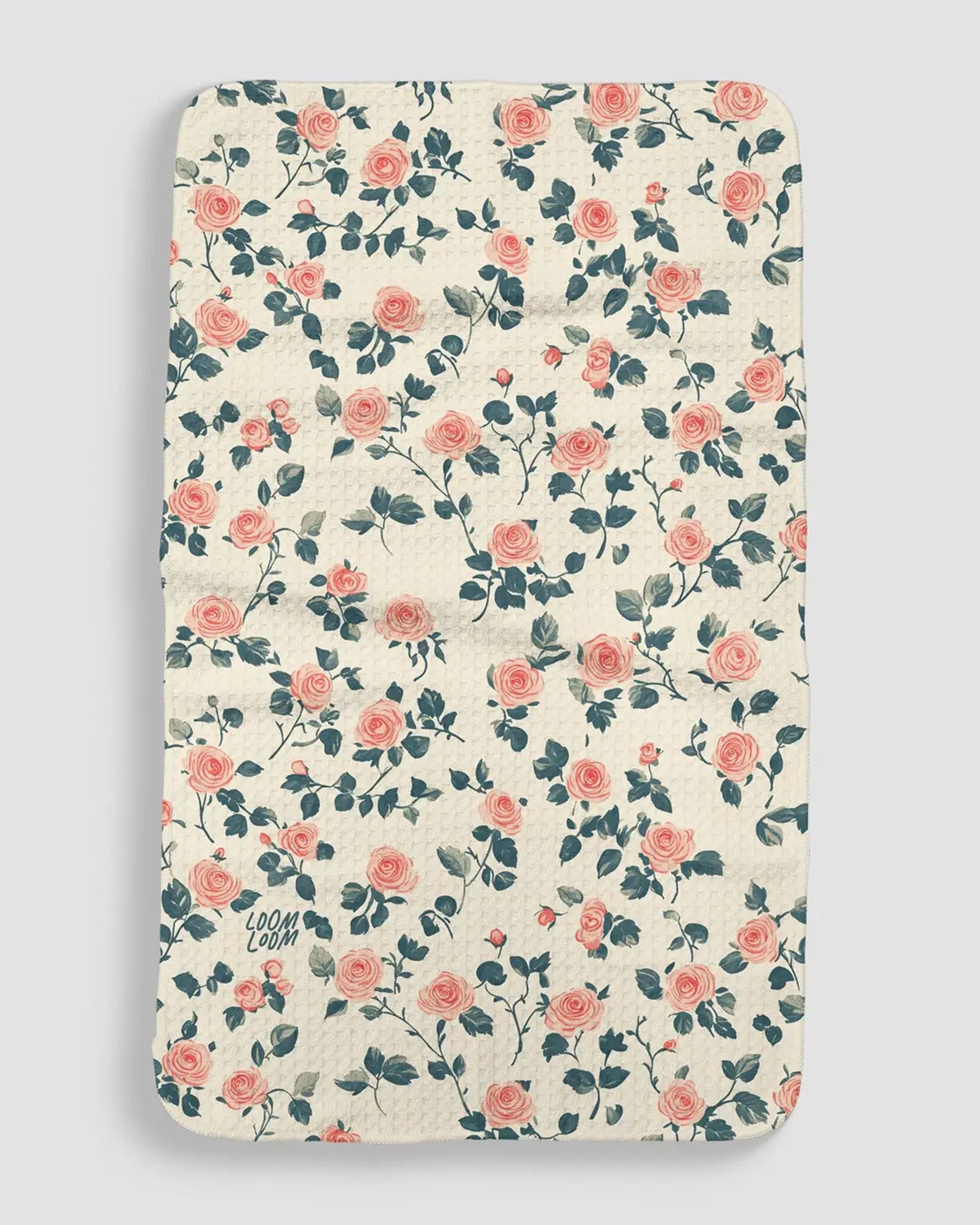 The Faire Roses Towel features a rectangular quilted design with a cream base, pink rose and green leaf pattern, EcoLoom fabric, rounded corners, and "LOOM LOOM" logo in one corner.