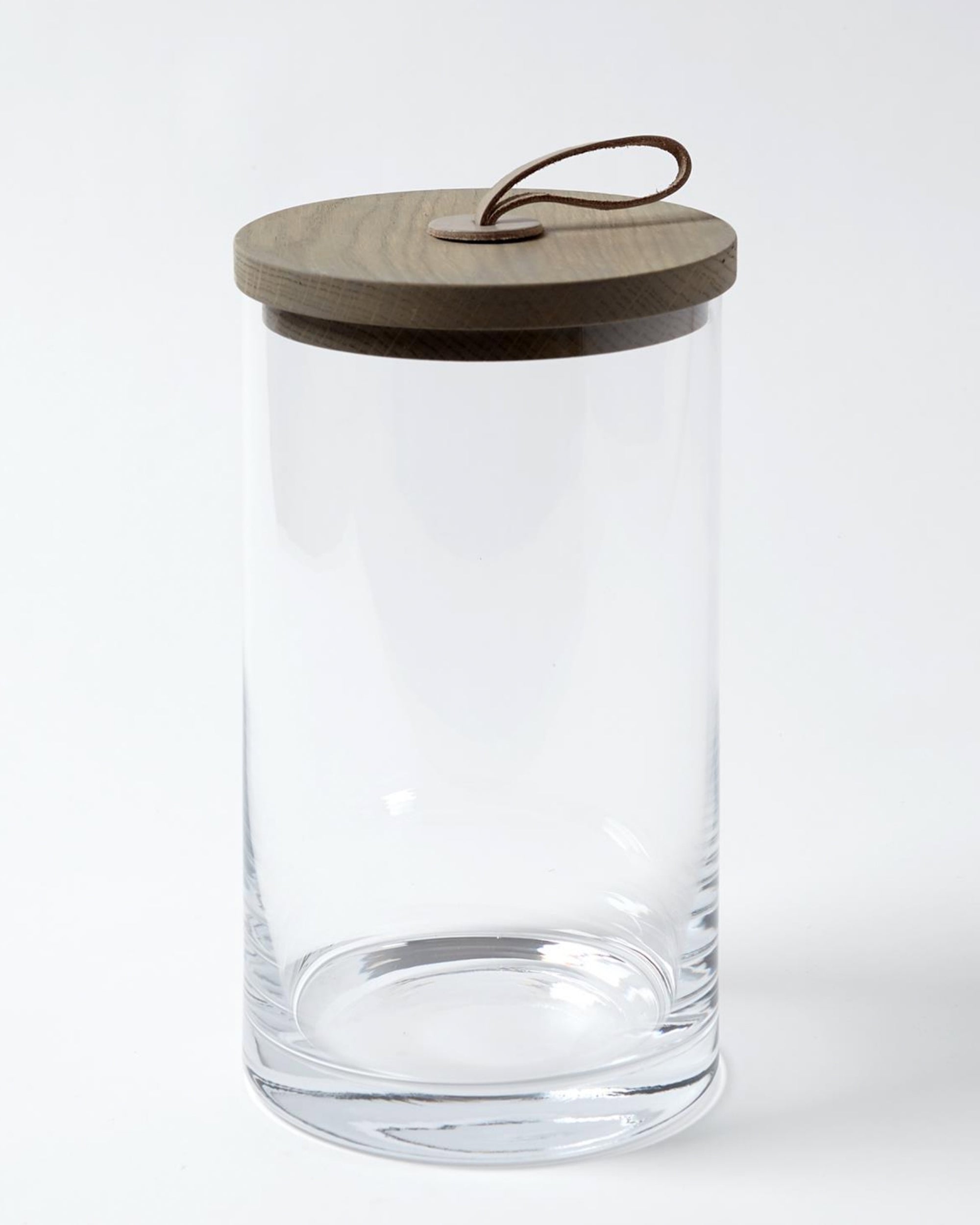 The Global Views BB-6.60025 Rustic Canister LG features clear glass, a flat wooden lid, and leather loop handle—perfect for adding Chalet Collection-inspired rustic charm to your kitchen. Shown on a plain white background.